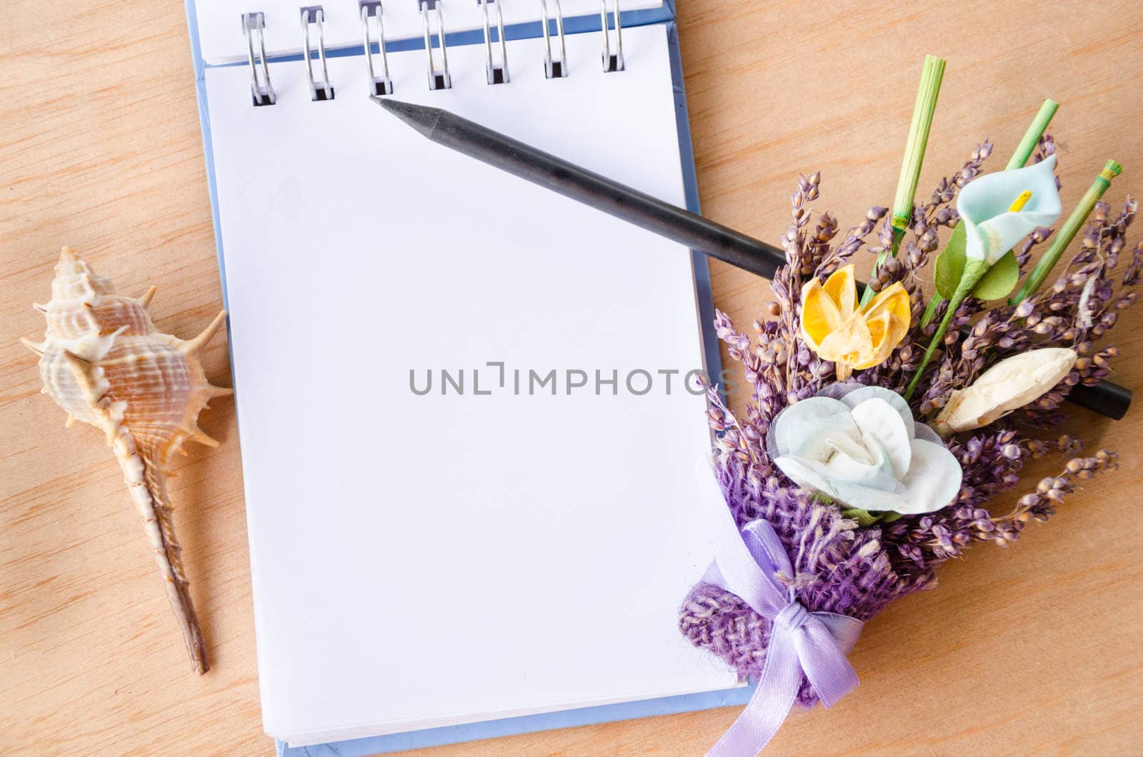 Blank open diary and black pencil with flower on wooden background. Free space for your text.