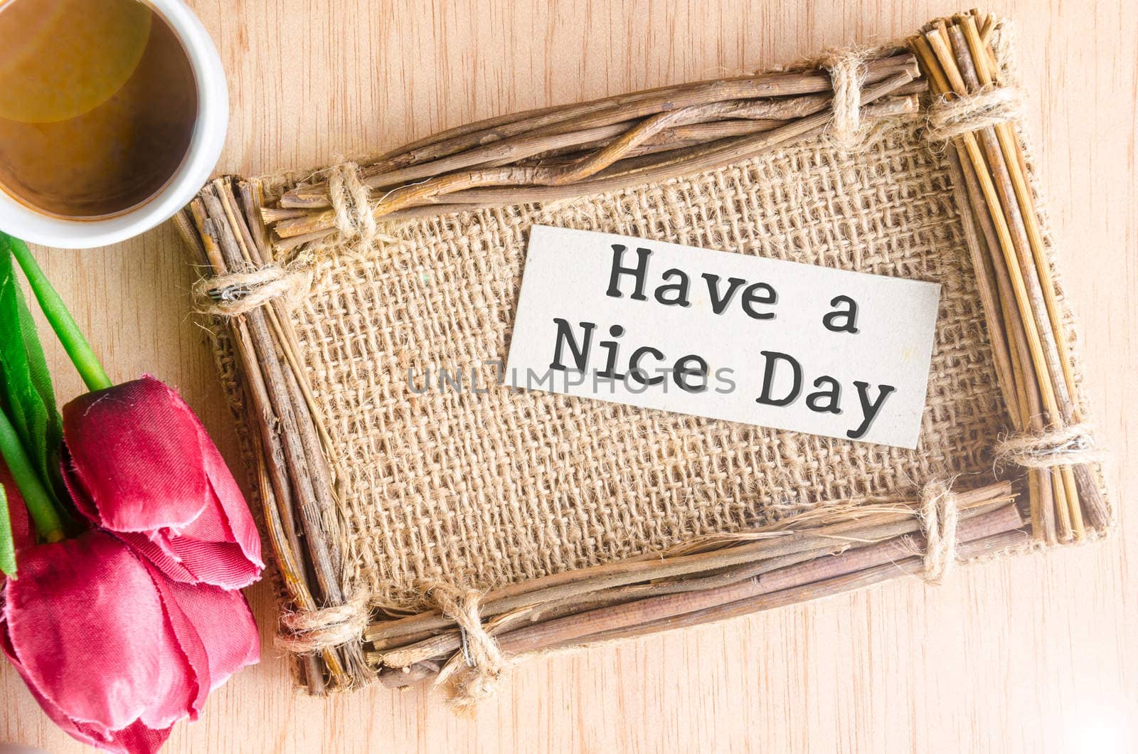 Have a nice day paper tag in sack photo frame and coffee with red tulip on wooden background.