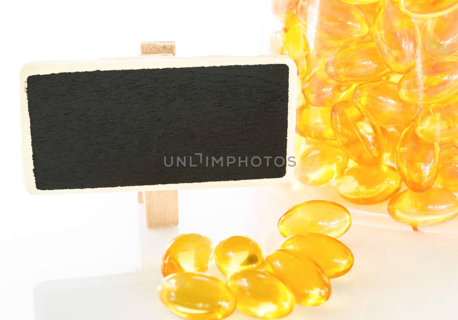 Fish oil capsules on white background and blank wooden tag.