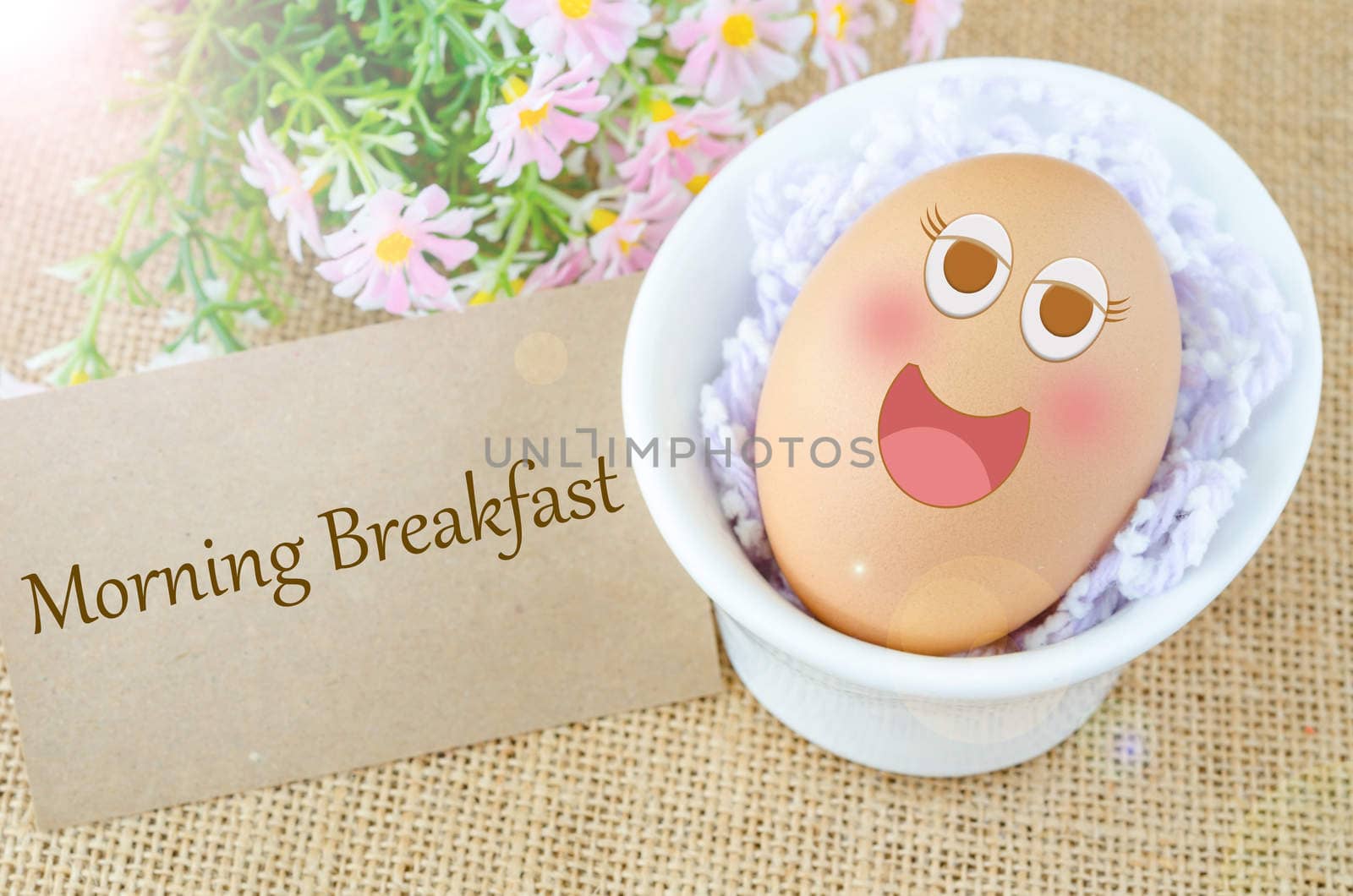 Morning breakfast and smile face egg in white cup with flower on sack background.