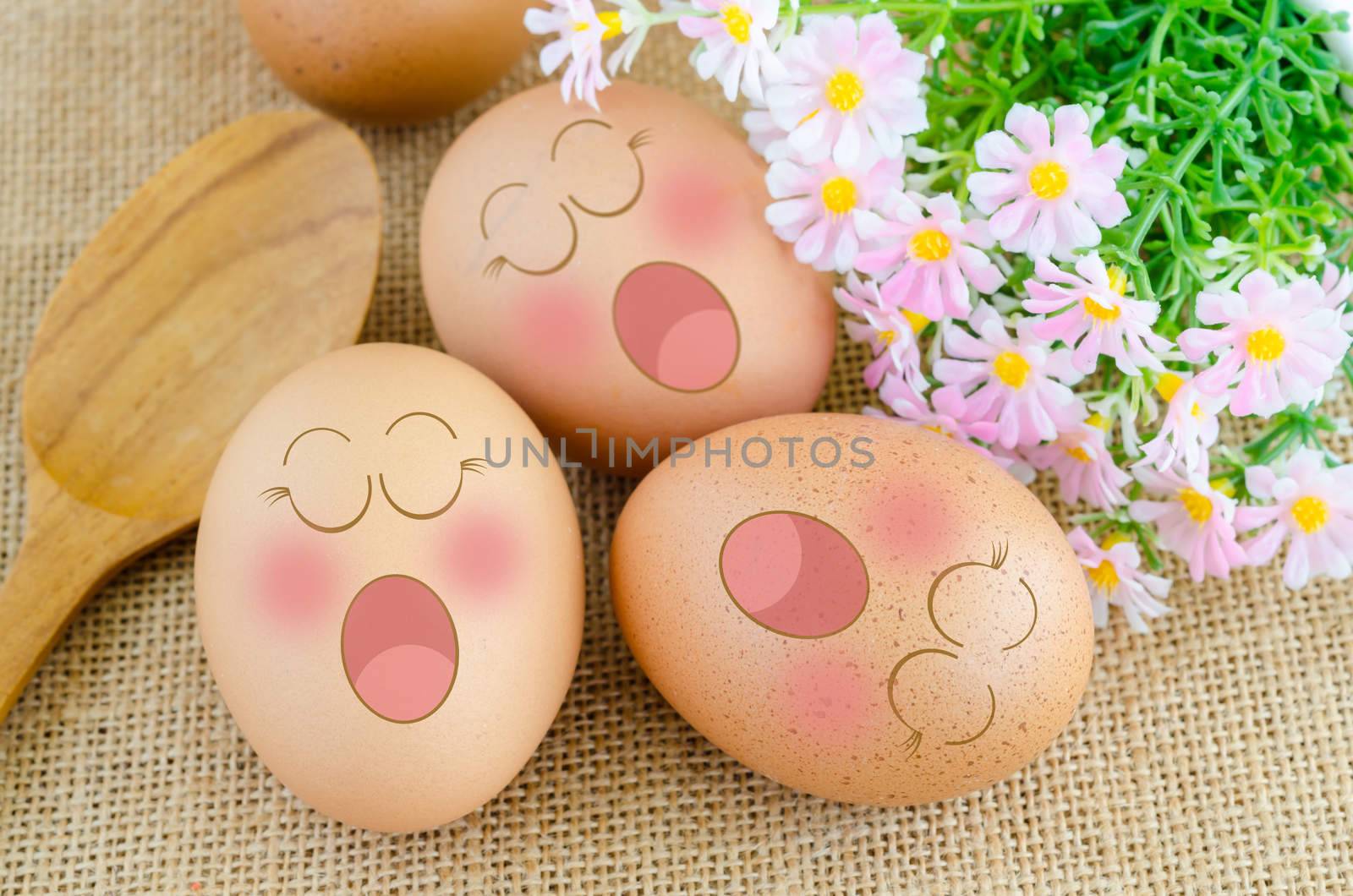 Eggs sleep in Expression Face ans wooden spoon with flower on sack background.