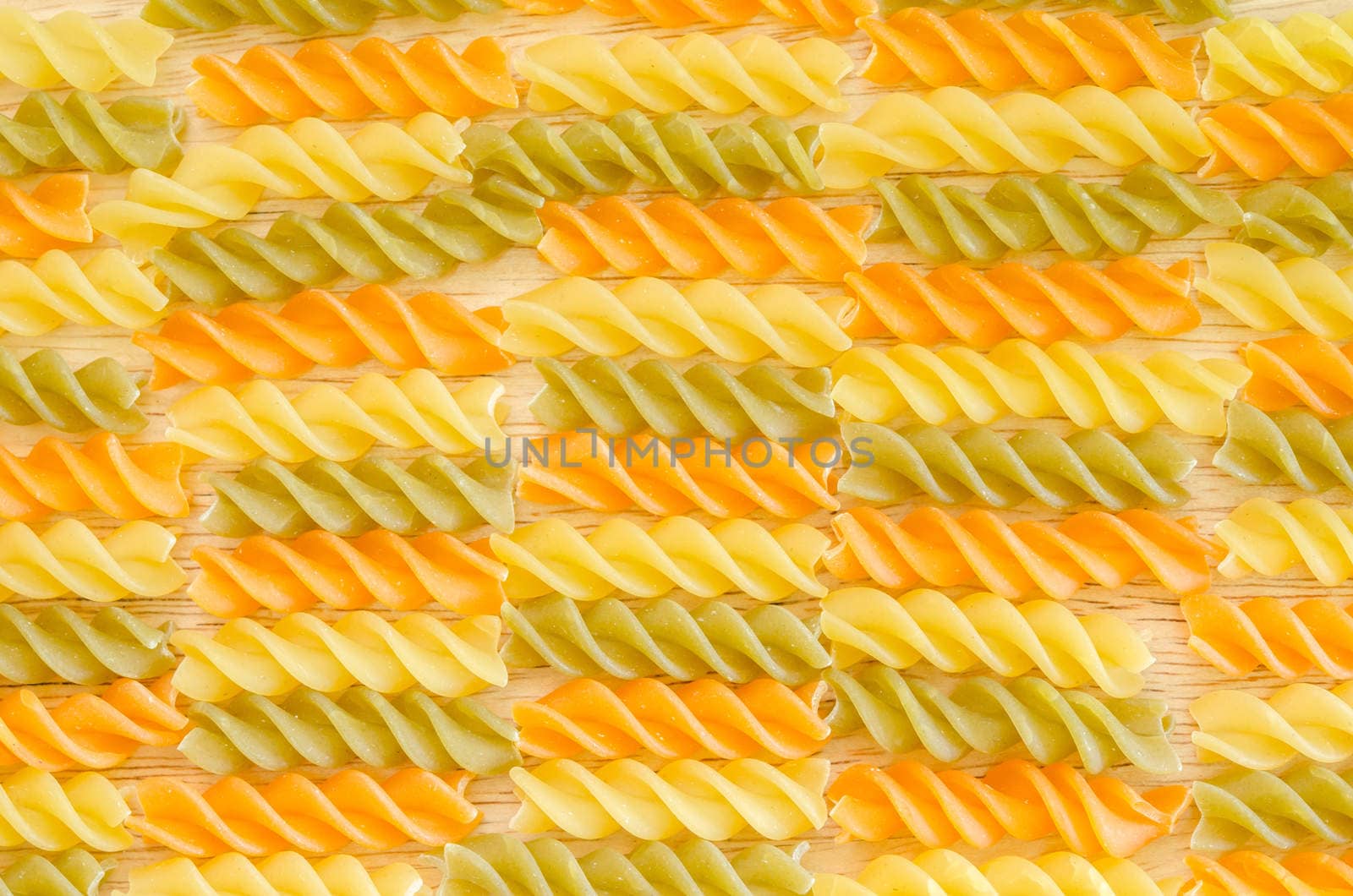 Color penne pasta. Tomato, spinach and wheat pastas texture as background.