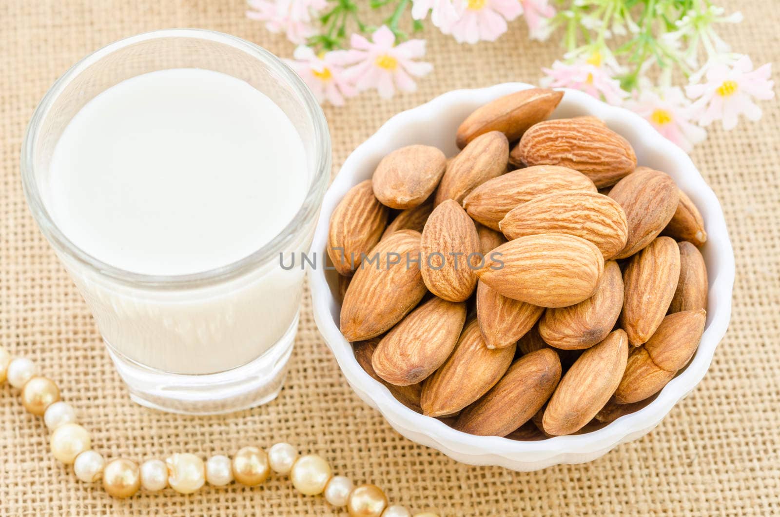Almond milk in glass and almonds in white cup. by Gamjai