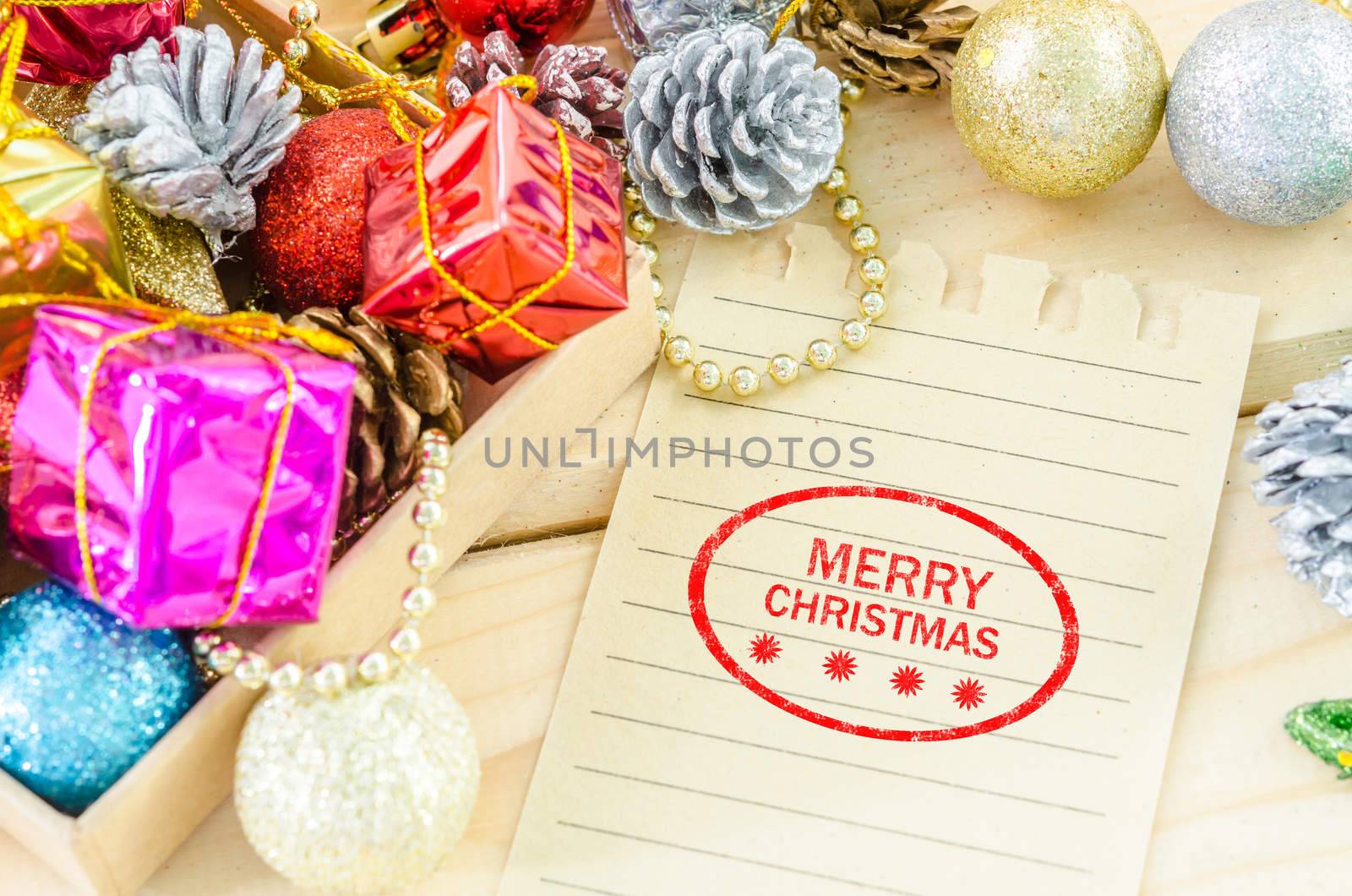 Banner and logo saying merry christmas on brown paper with christmas decorations on wood background.