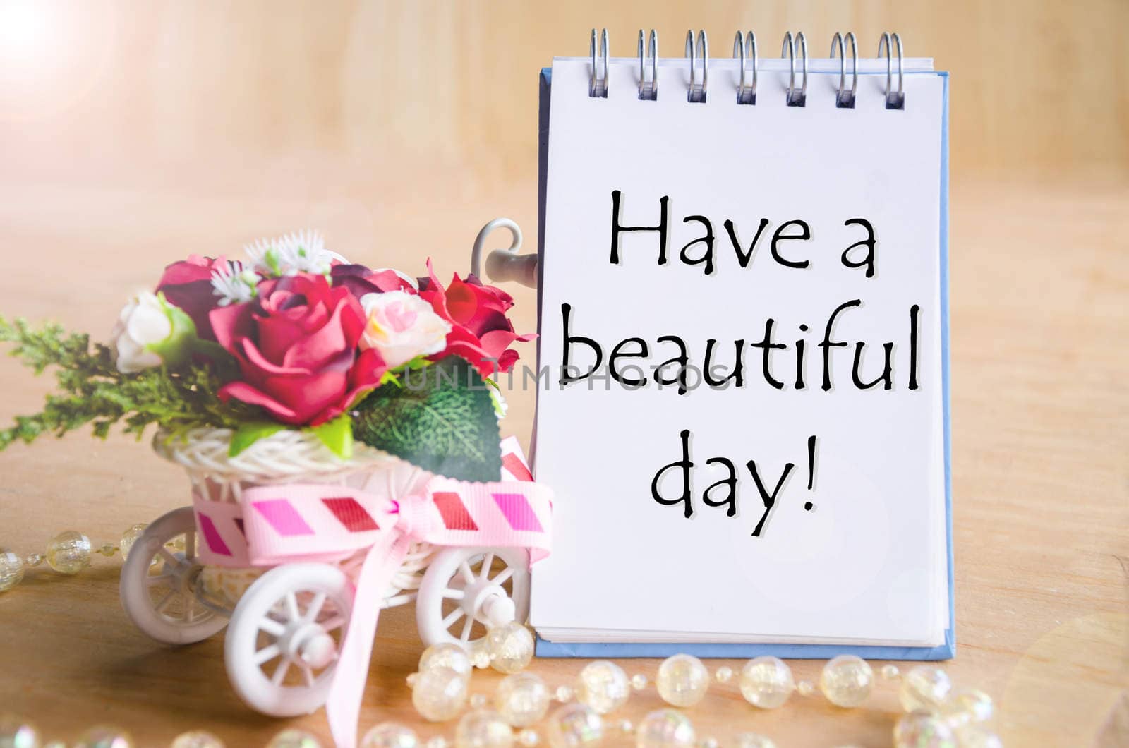 Have a nice day on open diary and and red rose basket on wooden background.