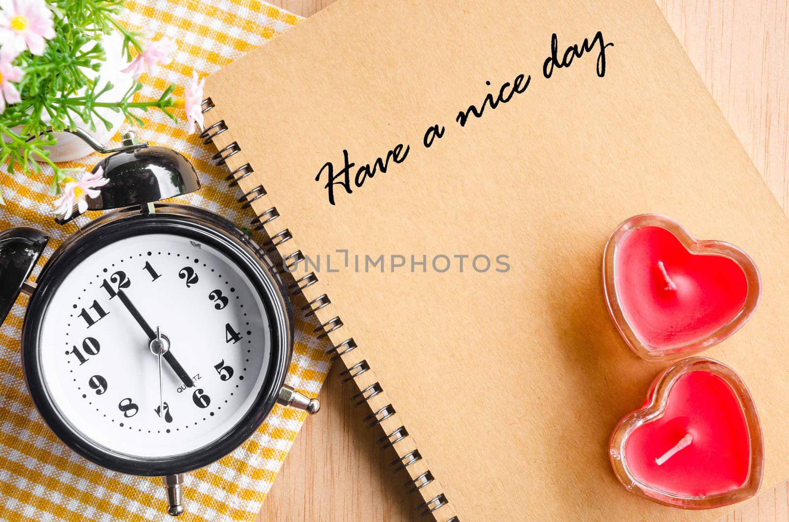 Have a nice day on brown diary and alarm clok with red heart on wooden background.