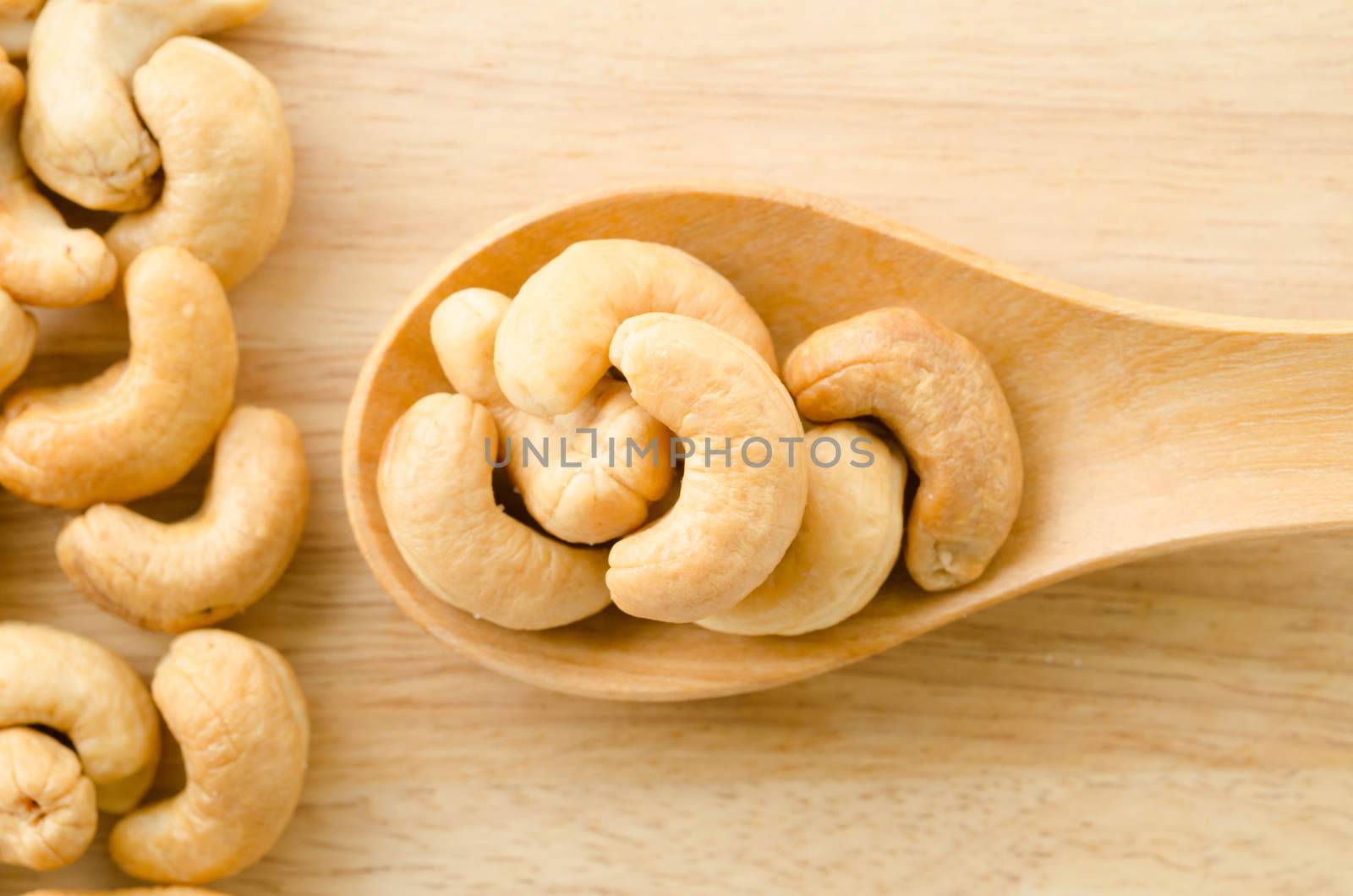 Roasted cashews on natural wooden background.