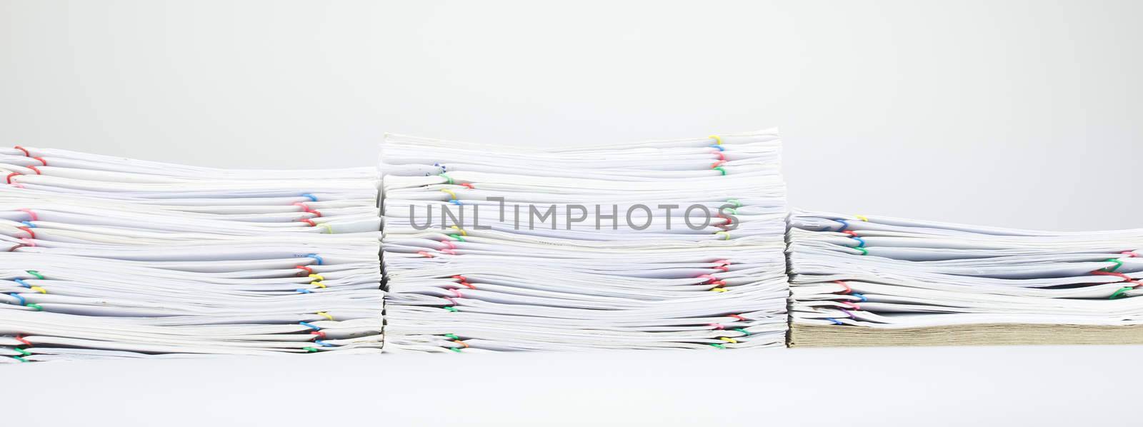 Colorful paper clip with pile of report and brown envelope on white table.