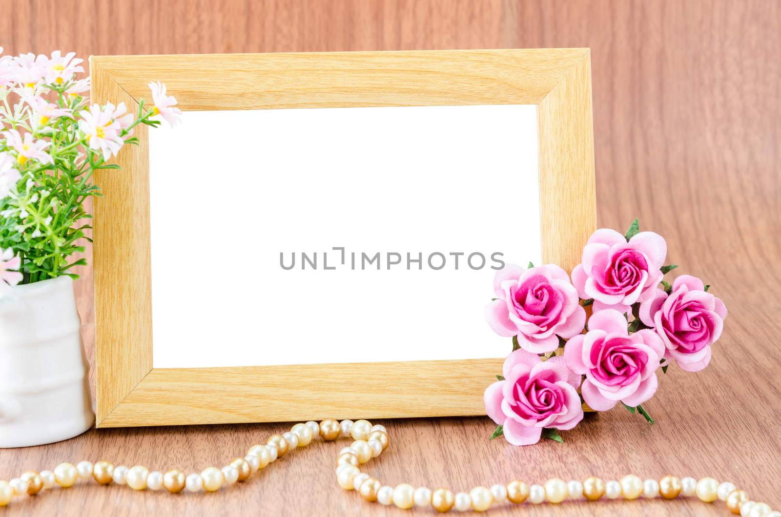 Blank wooden photo fame and pink flower on wooden background. Save with clipping path.