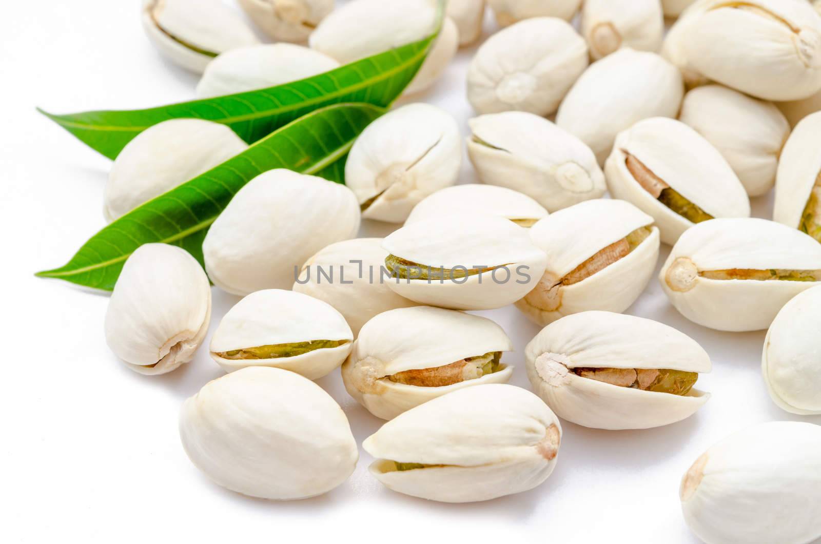 Dried pistachios nuts and green leaf on a white background