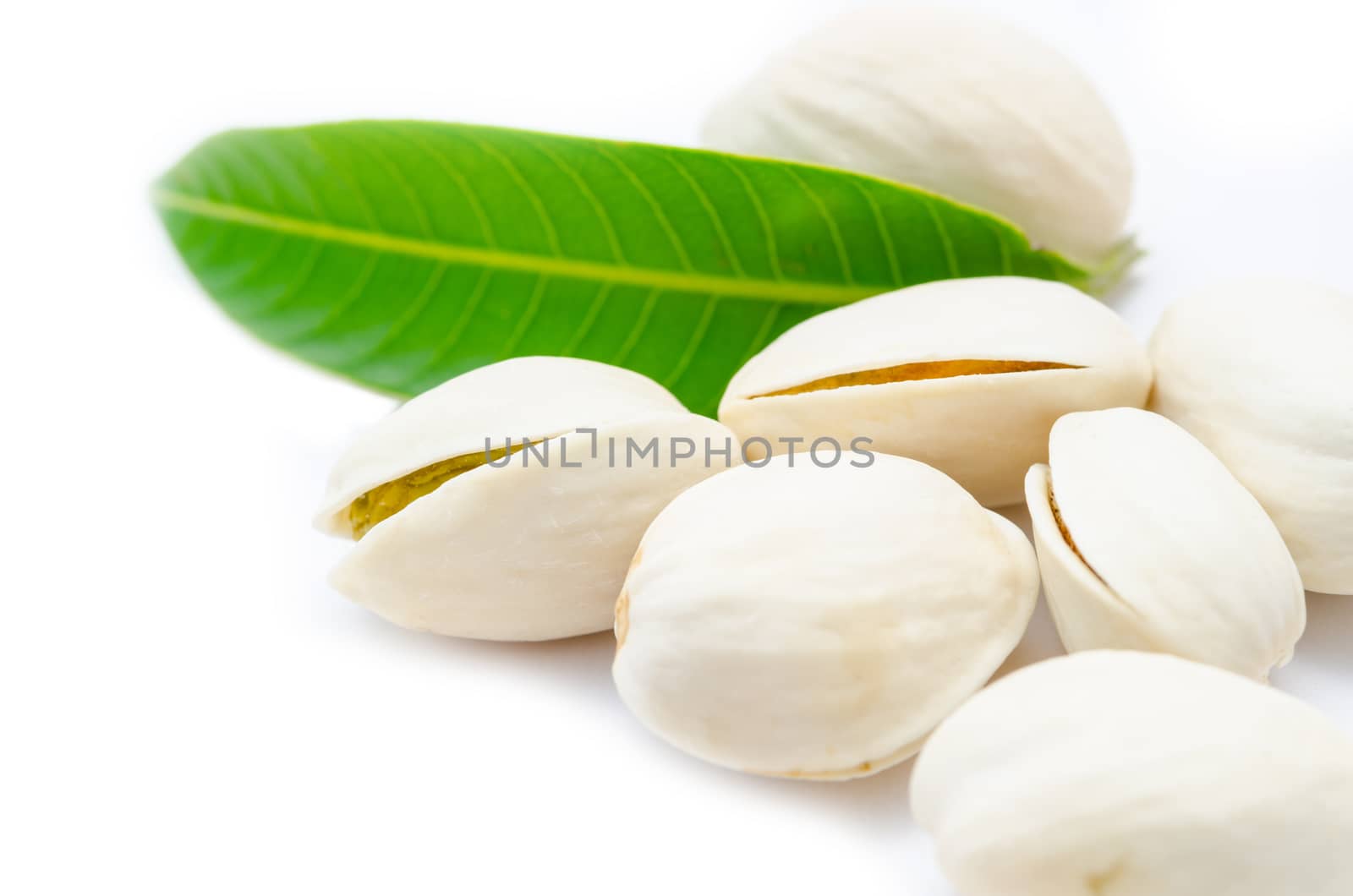 Pistachio nuts, fruits and green leaf isolated on white background