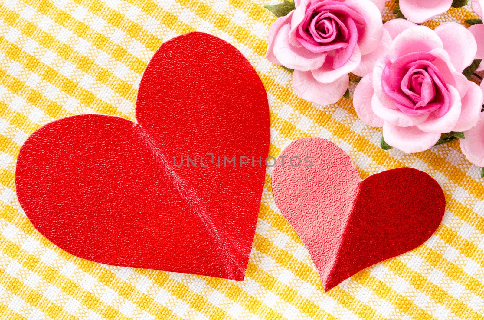 Red heart tag paper and pink rose flower on beautiful fabric background.