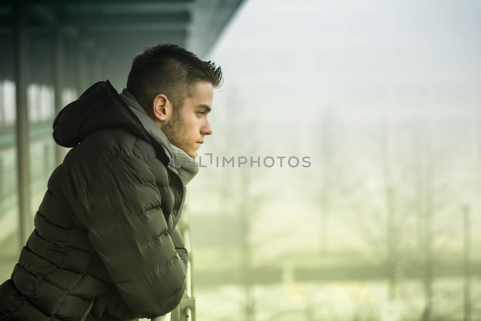 Profile view of handsome young man outdoor in winter wearing scarf, looking away thinking