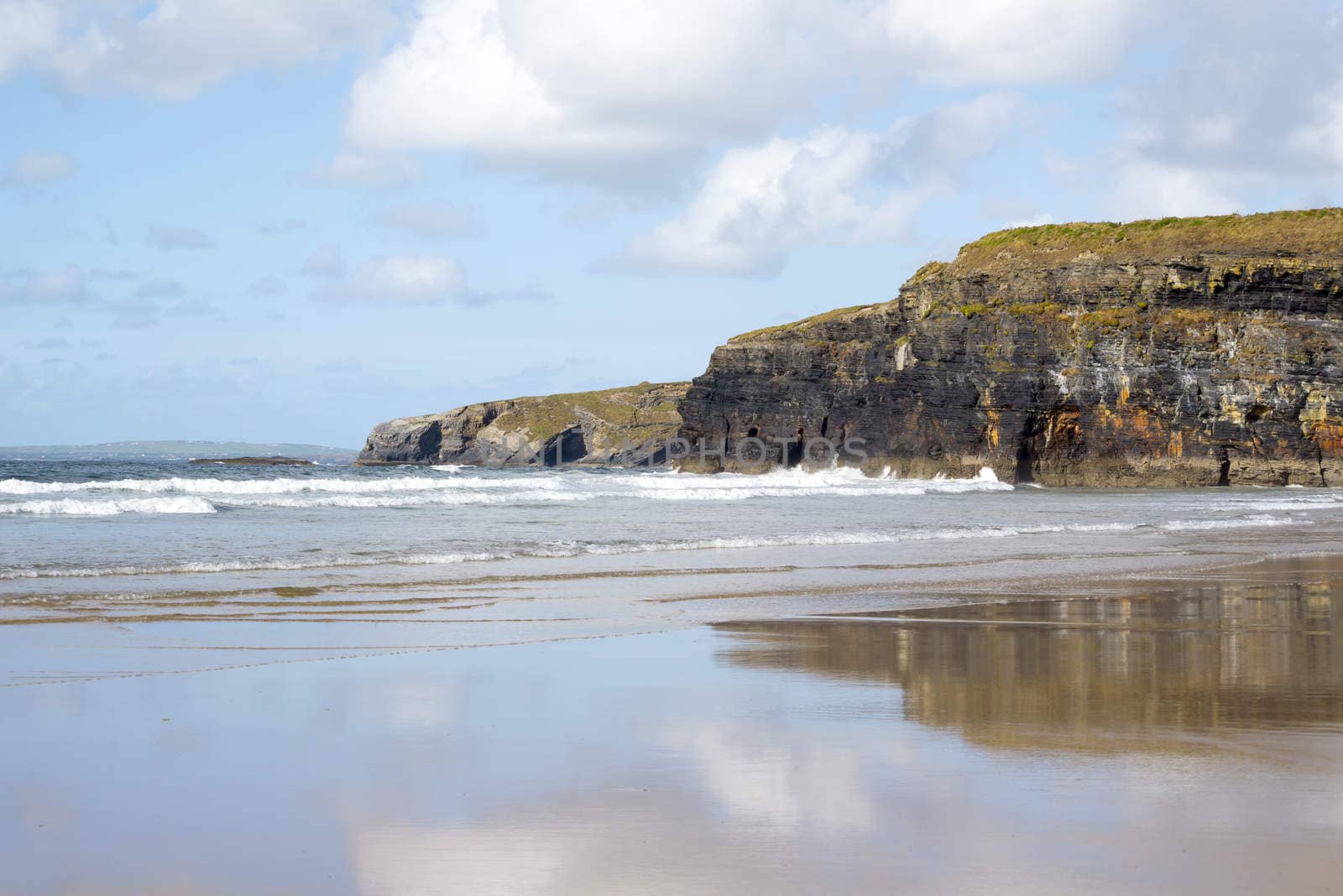 beautiful soft waves break on the beach cliffs at ballybunion