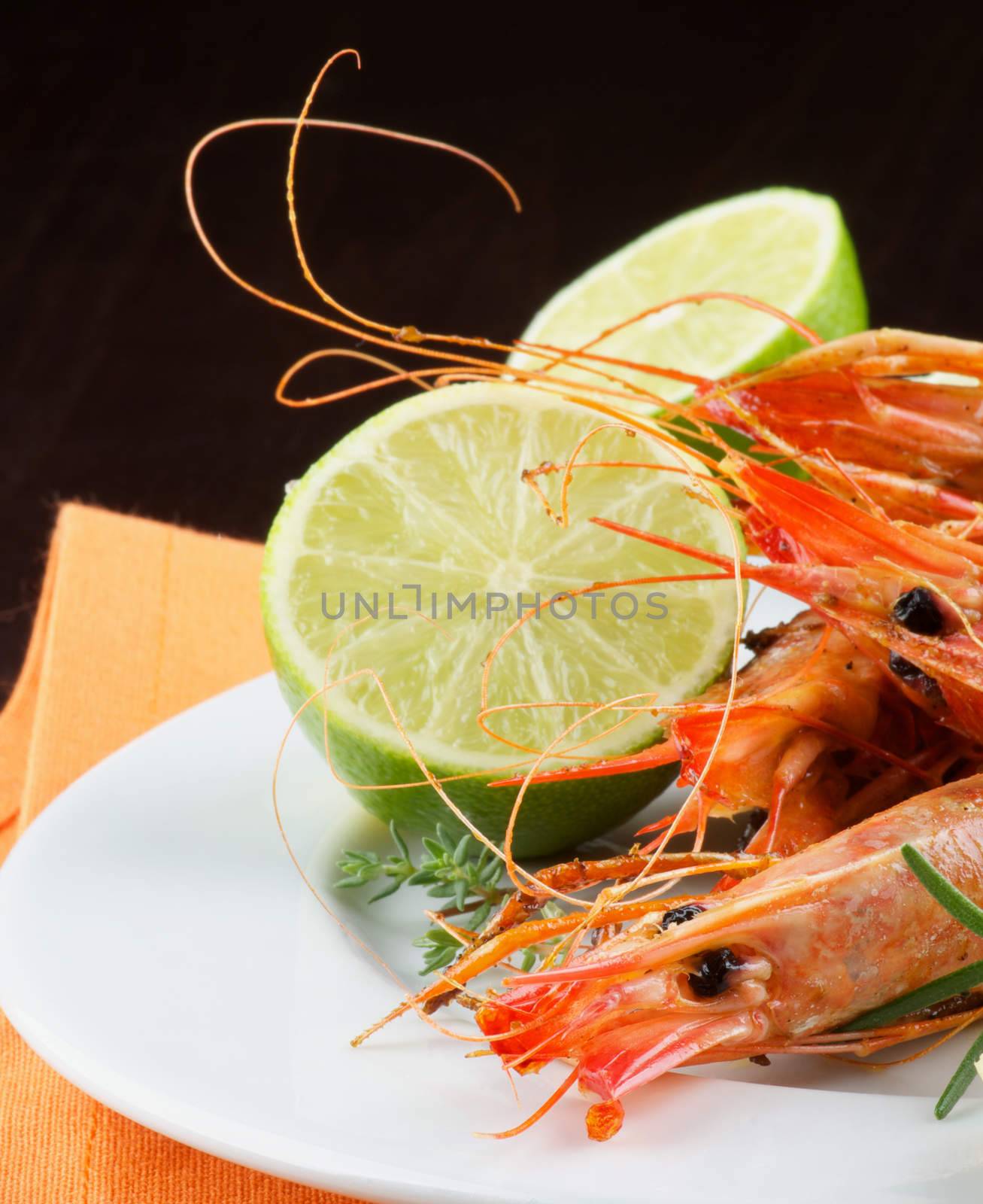 Delicious Roasted Shrimps with Lime on White Plate with Orange Napkin Cross Section on Dark Wooden background