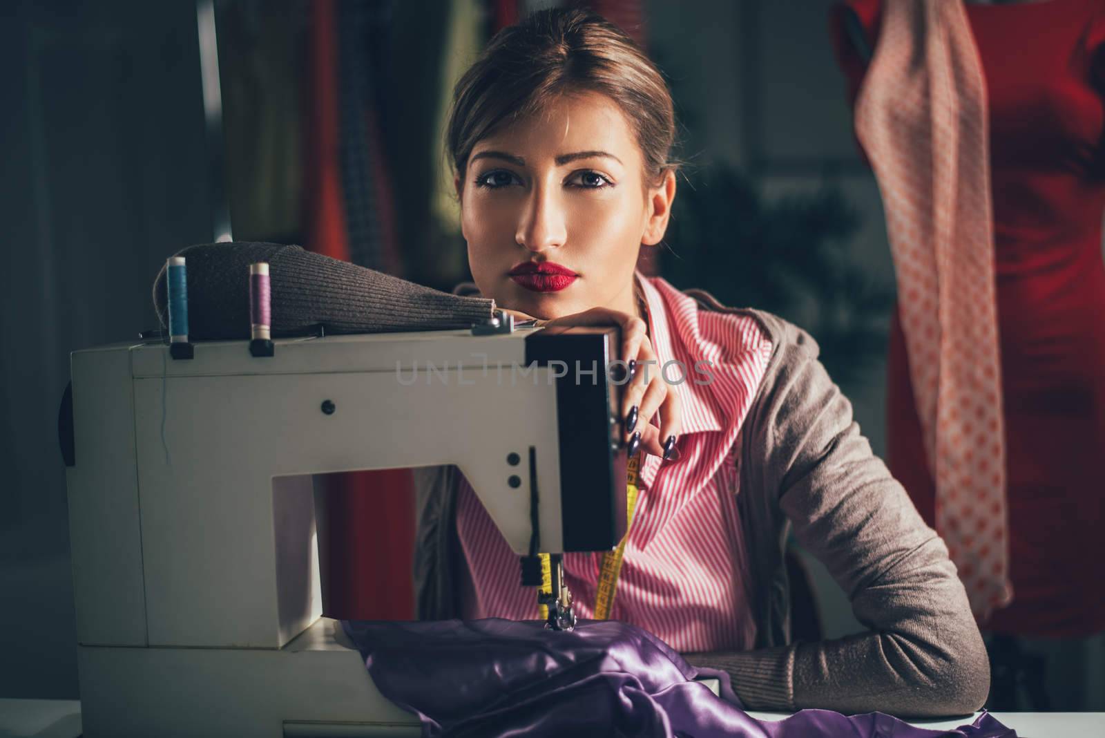 Beautiful tired woman sits in front of the sewing machine and thinking. Looking at camera. Vintage concept.