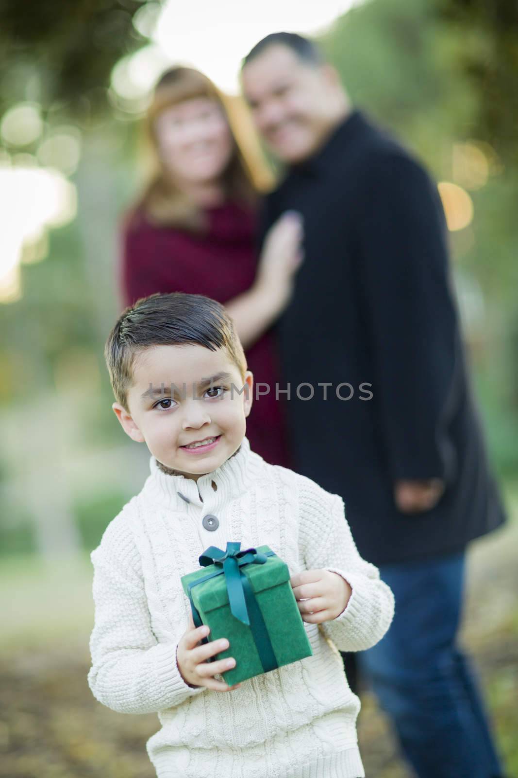 Young Mixed Race Boy Holding Gift In Front with Parents Behind.
