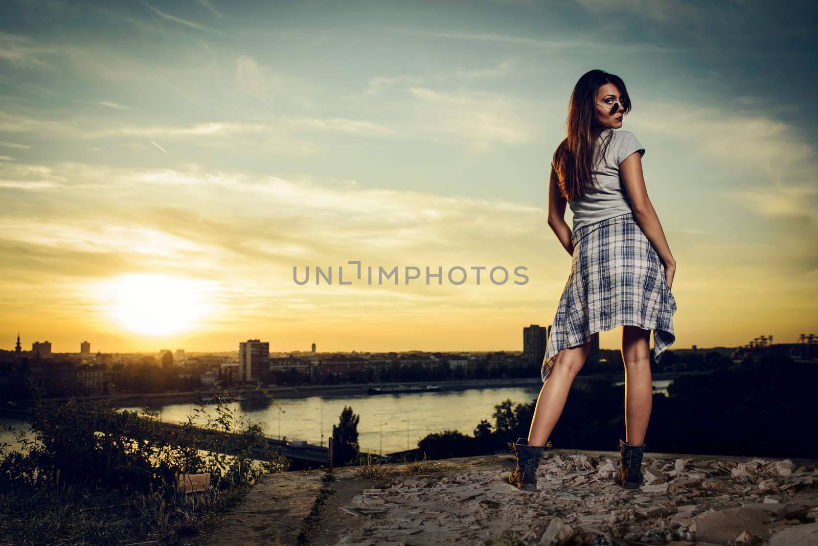 Fashion girl posing in sunglasses at sunset above the city