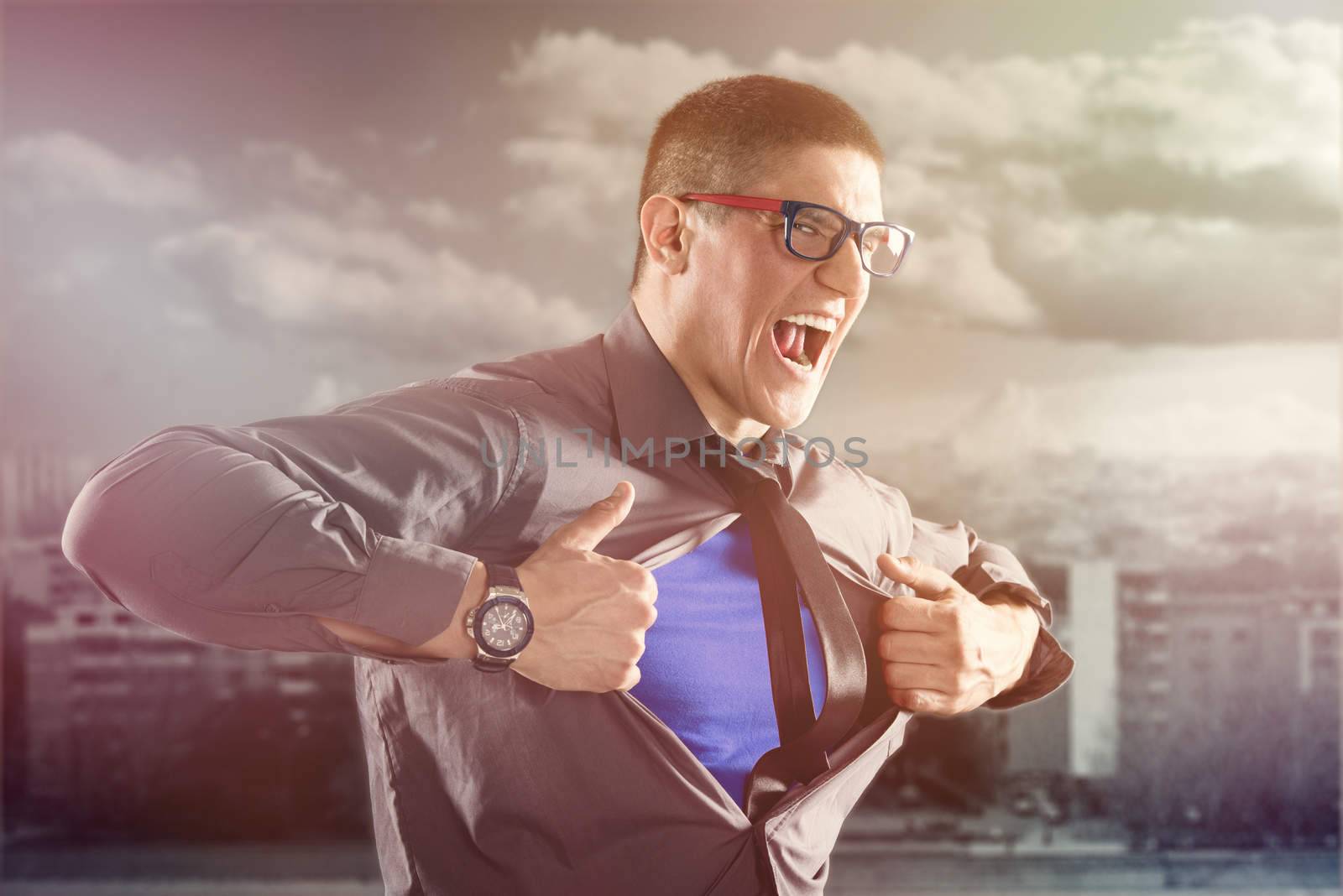Angry businessman ripping open his shirt and exposing a Superhero blue costume underneath. The man is wearing glasses and looking at camera.