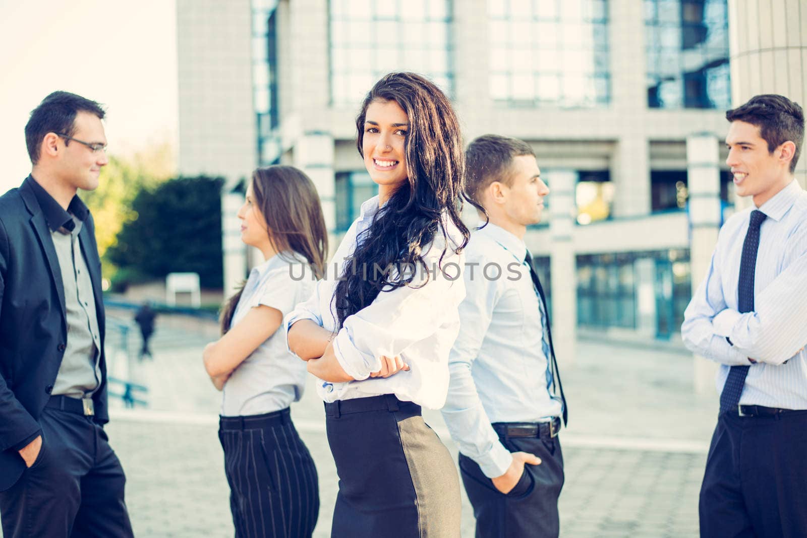 Portrait of a beautiful young businesswoman with her team young business people standing in front of office building.