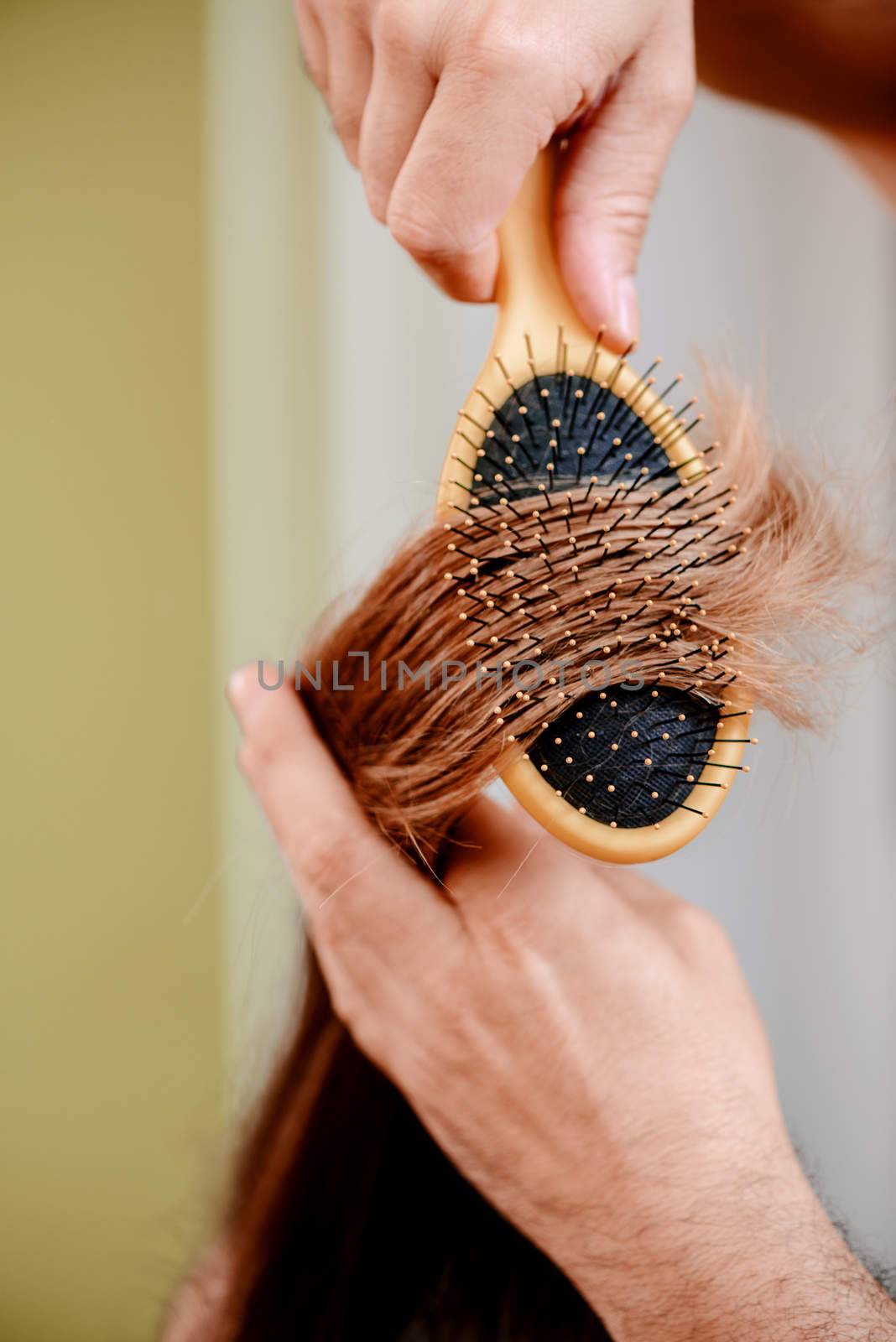 Close up of a drying long brown hair with round brush. 