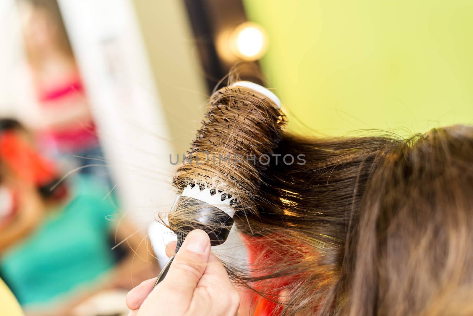 Close up of a drying long brown hair with round brush. 