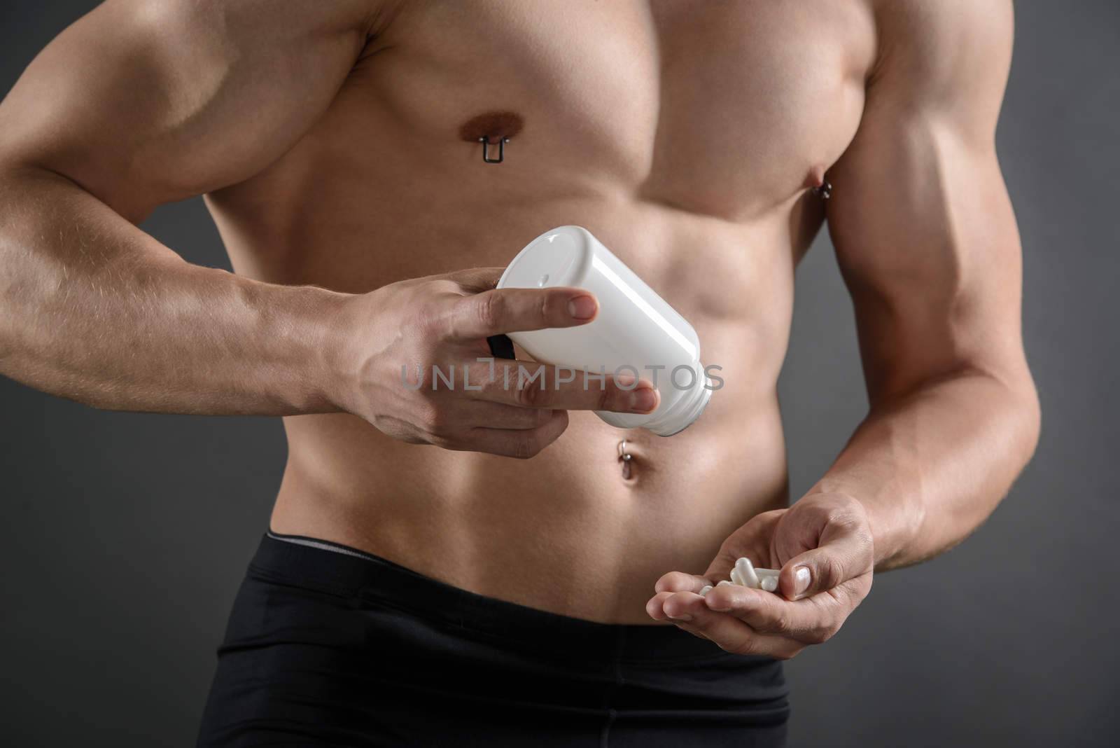 Close up of a body builder taking supplement pills