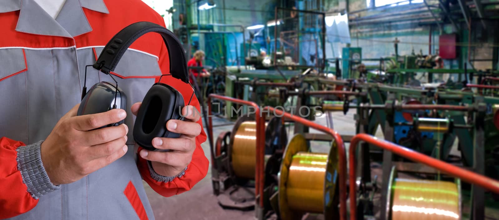 Worker with protective headphone at man hands at industrial factory