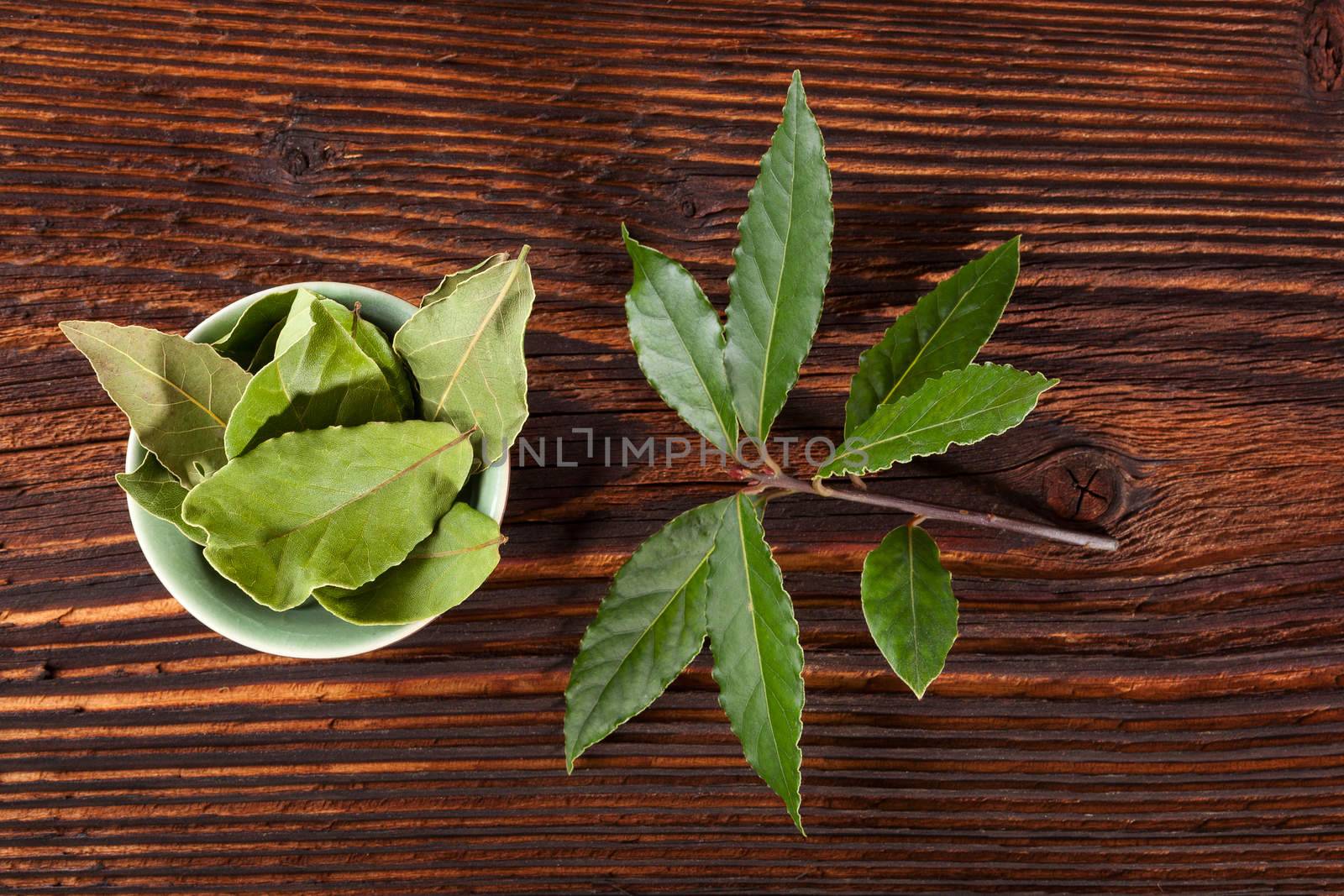 Fresh and dry bay leaves on brown wooden background, top view. Culinary herb, cooking ingredient and medical herb. 