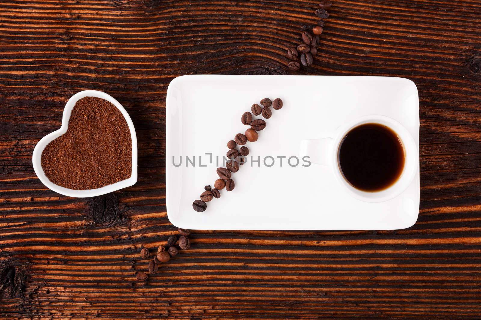 Coffee time. Cup of coffee, coffee beans and ground coffee in heart shape on wooden table, top view. Coffee break.