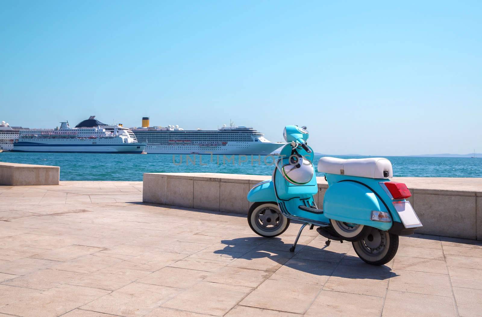 Blue scooter stands on the waterfront on the background of cruise ships in sunny weather
