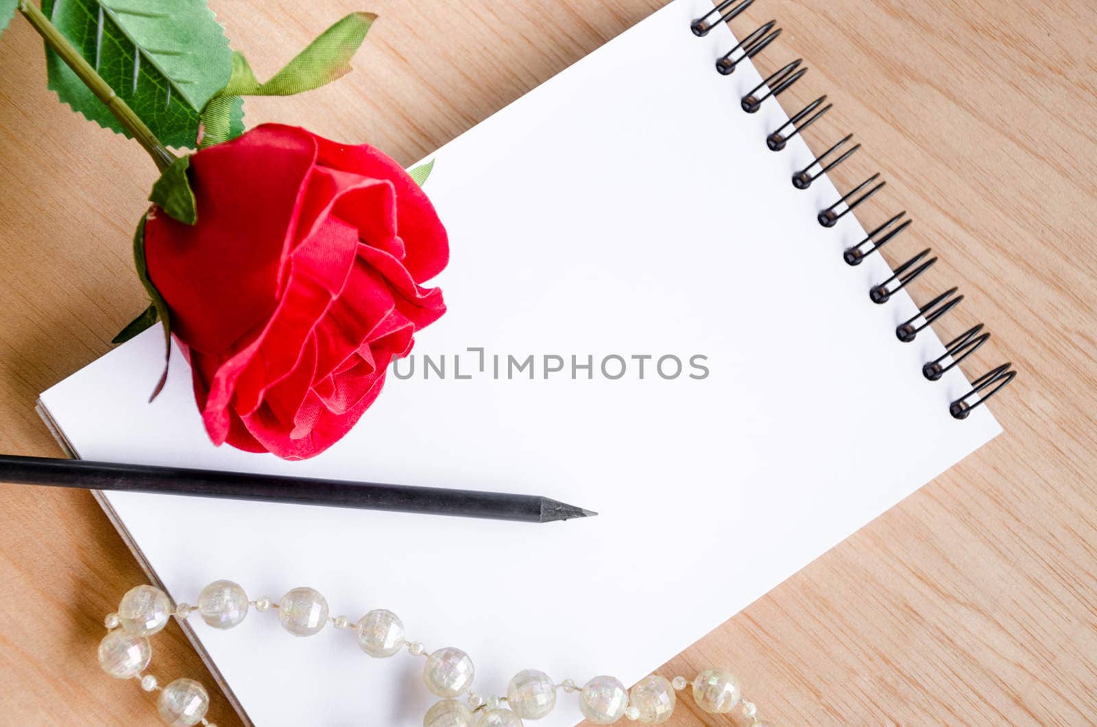 Focus Lovely red rose on a classic note book. on wooden bakcground.