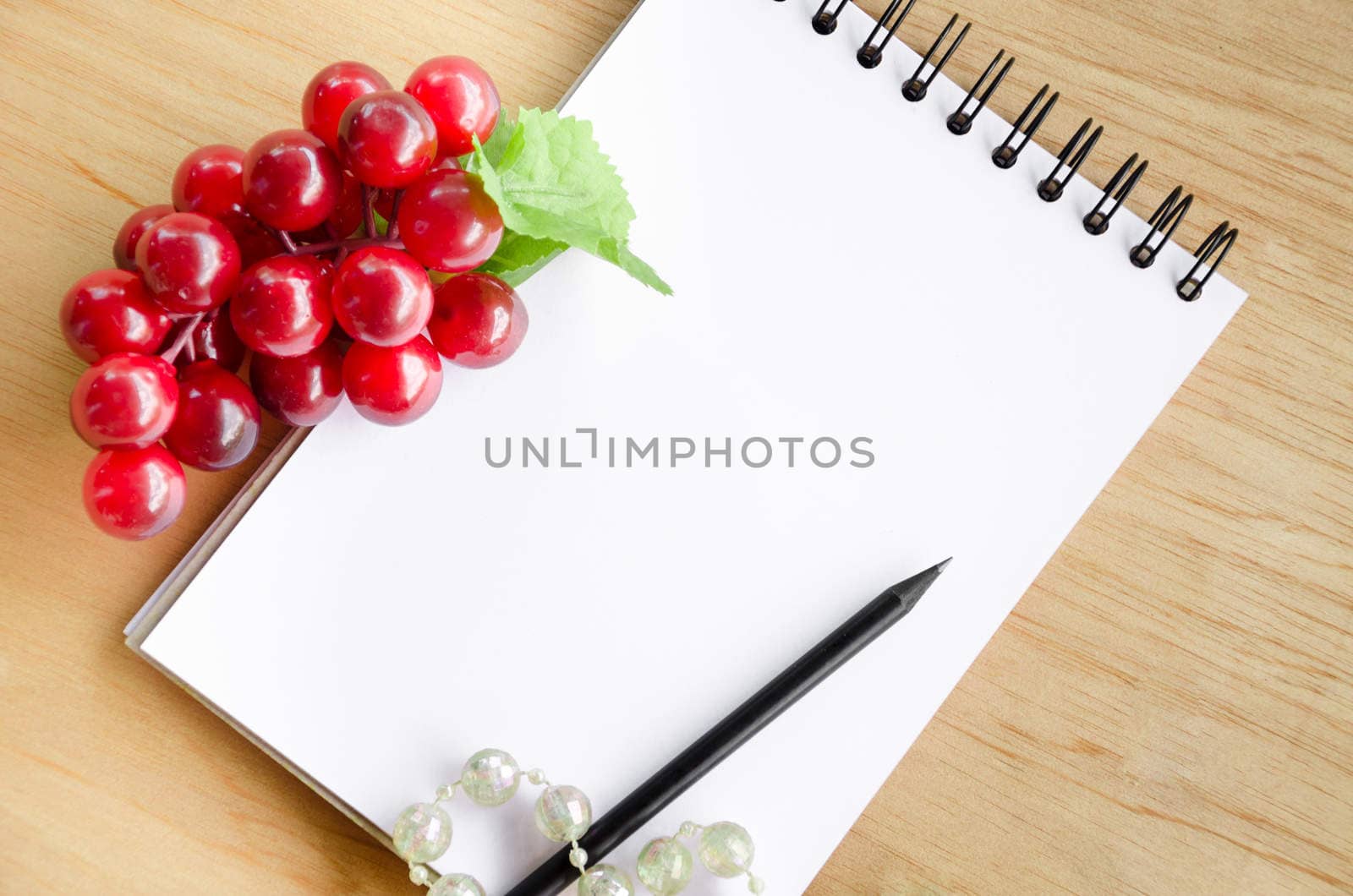 focus red grape and blank white diary on wooden background.