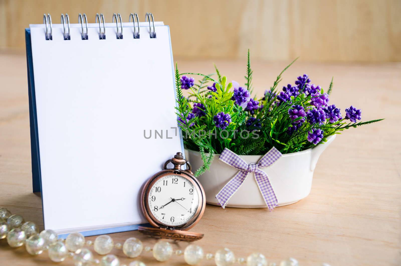 Open blank diary for your text and pocket watch with violet flower on wooden background.