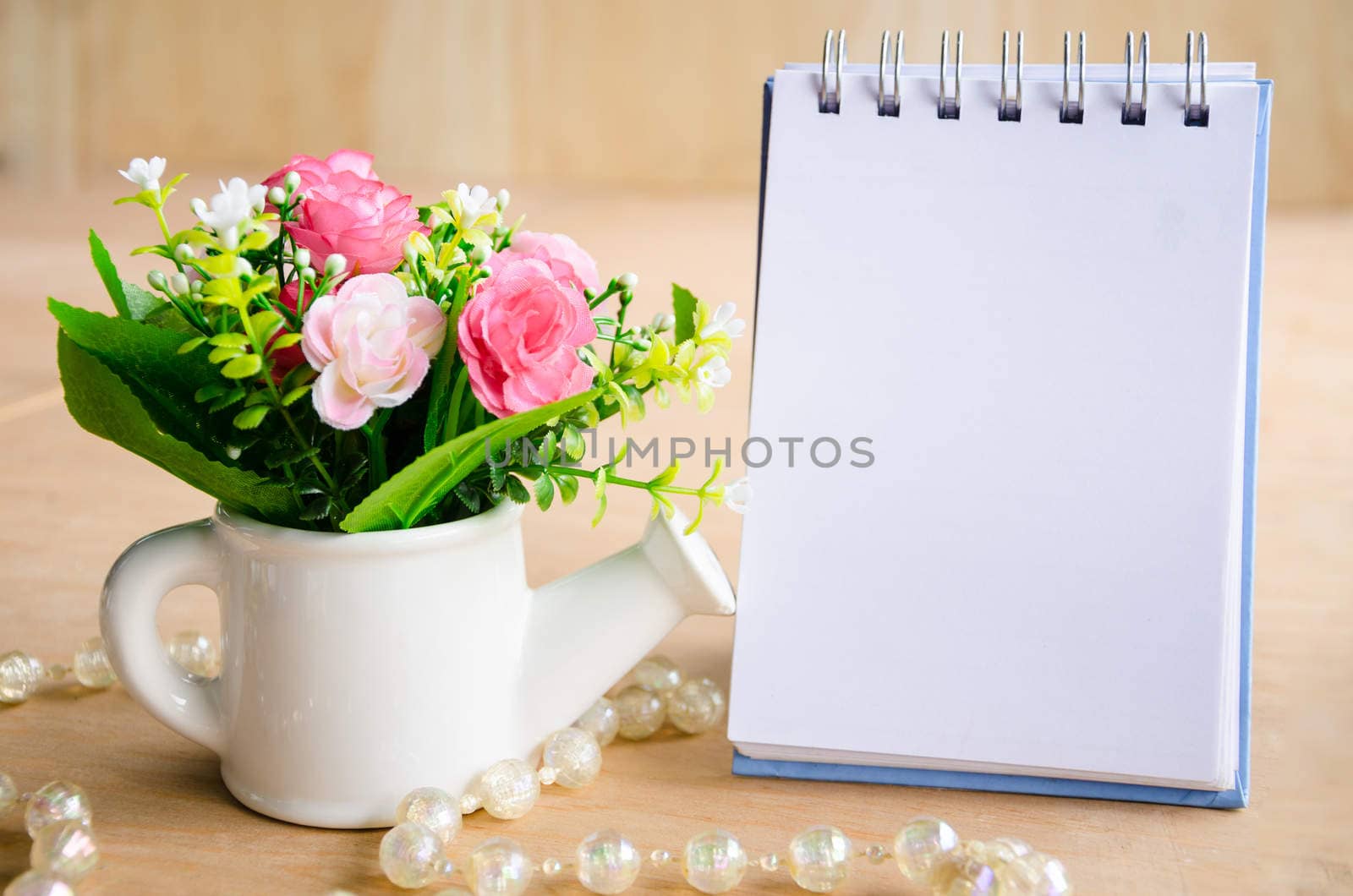 focus at flower with blank diary binder on wooden background.