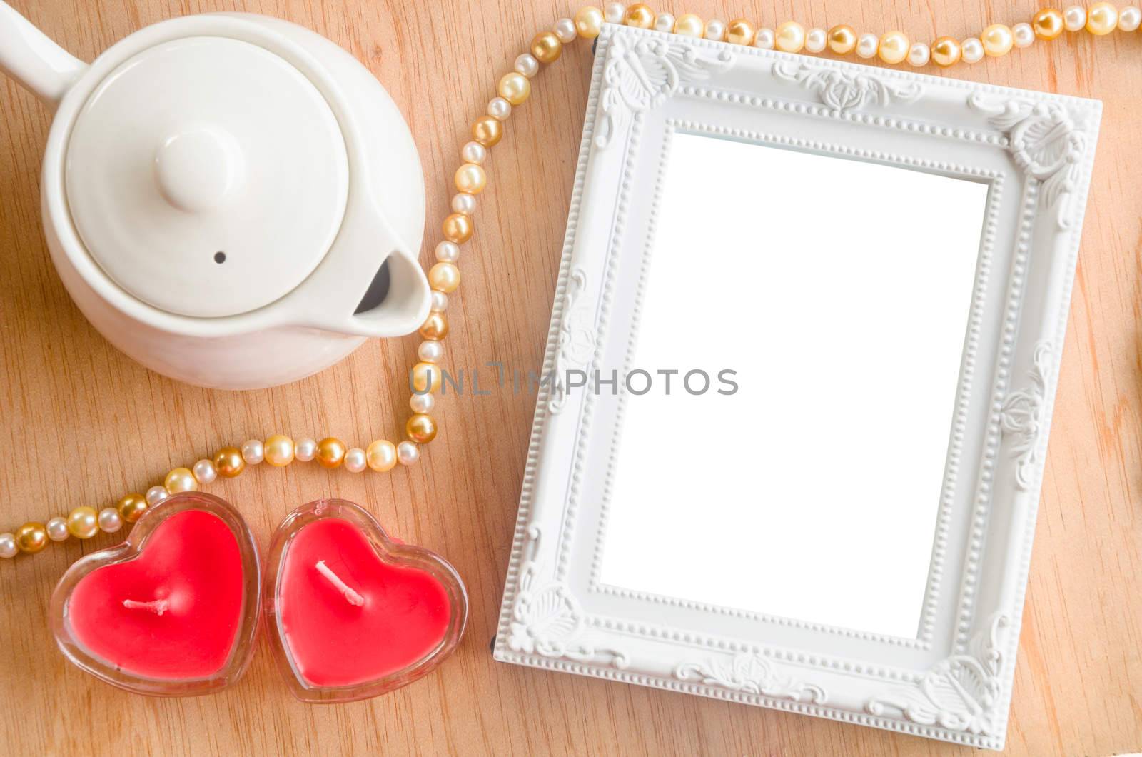 Vintage white photo frame and red heart shape candle on wooden background, clipping path.