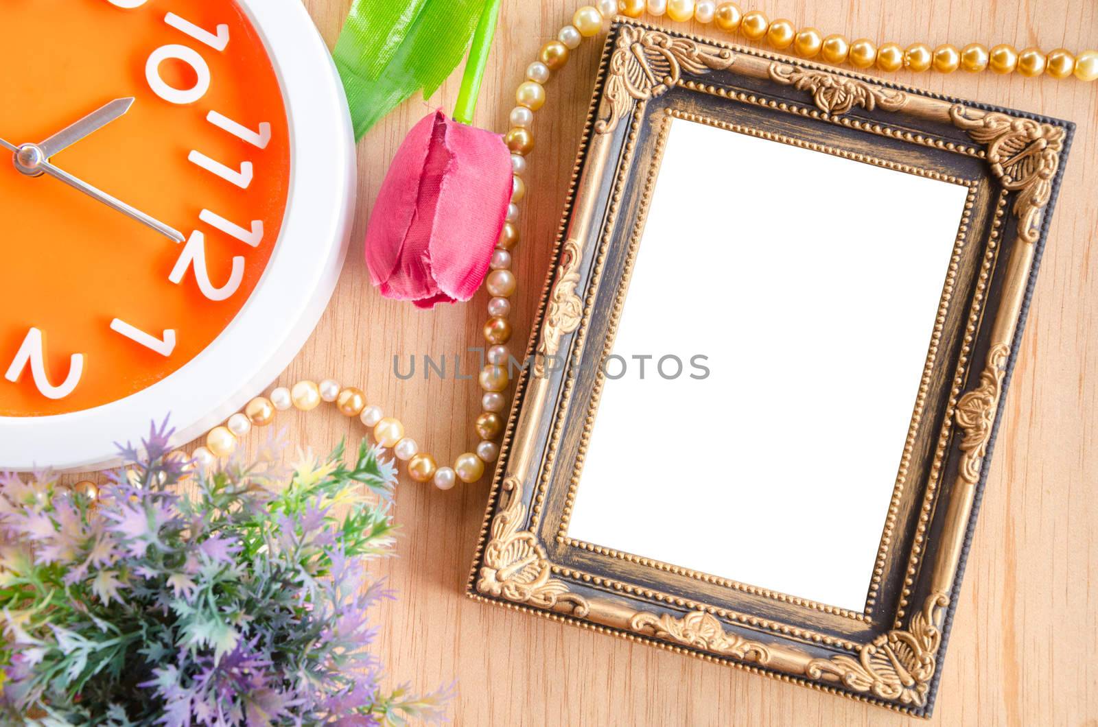 Vintage blank photo frame and clock with flower on wooden backgr by Gamjai