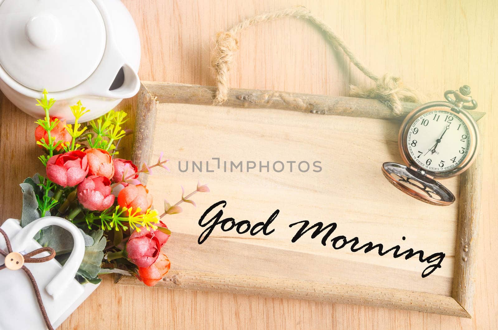 Good morning text in blank wooden photo frame with flower on wooden background.