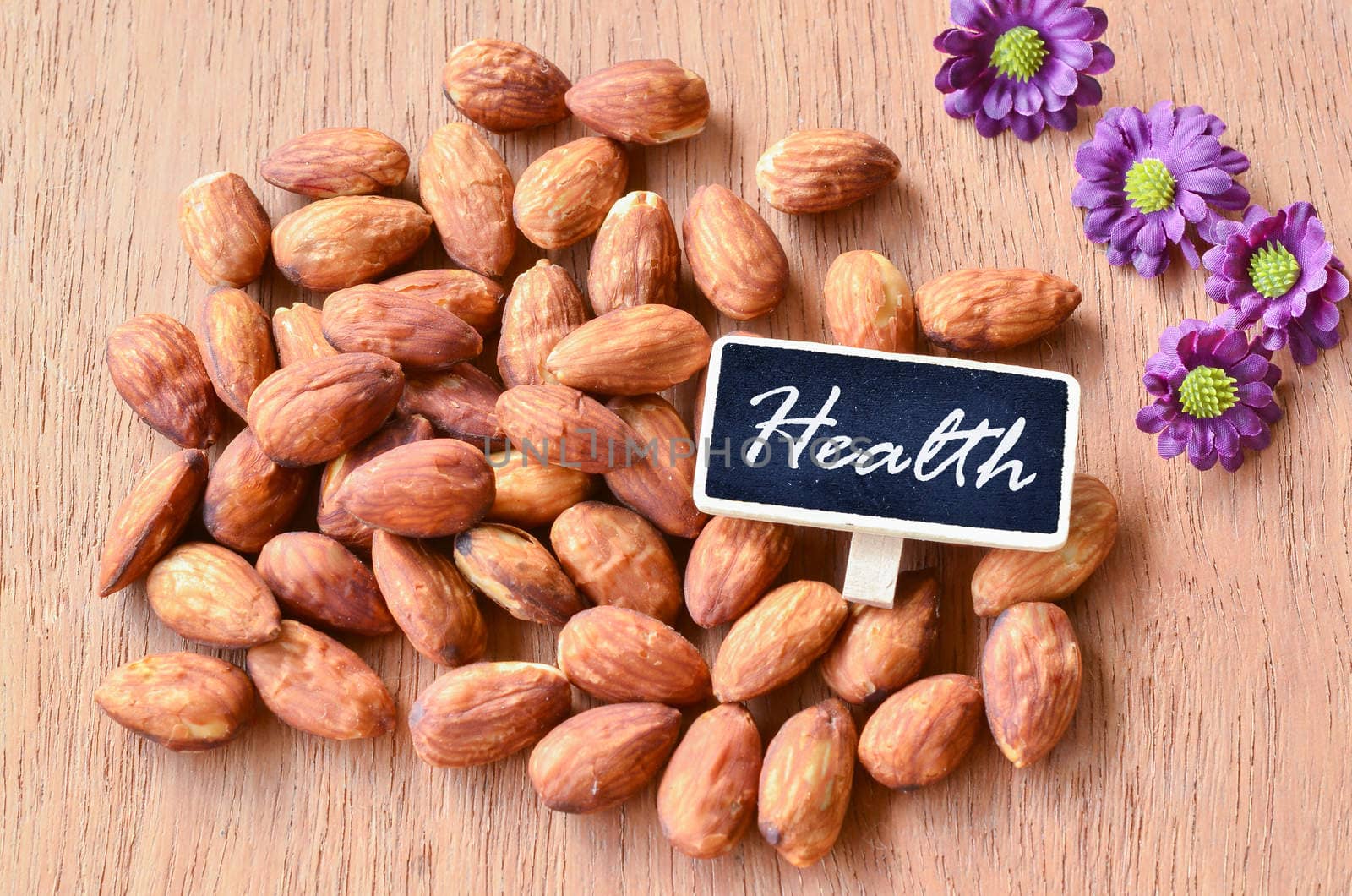 Almond and Health tag on wooden background. by Gamjai