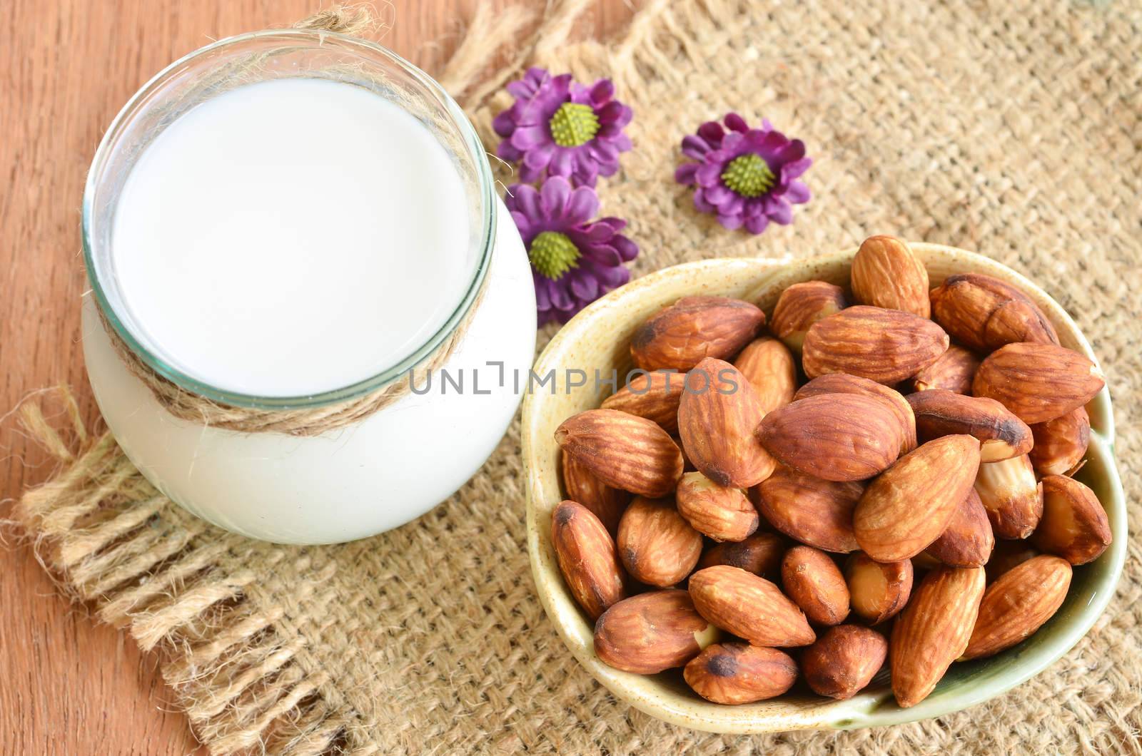 Almond with milk almond and violet flower on wooden background.