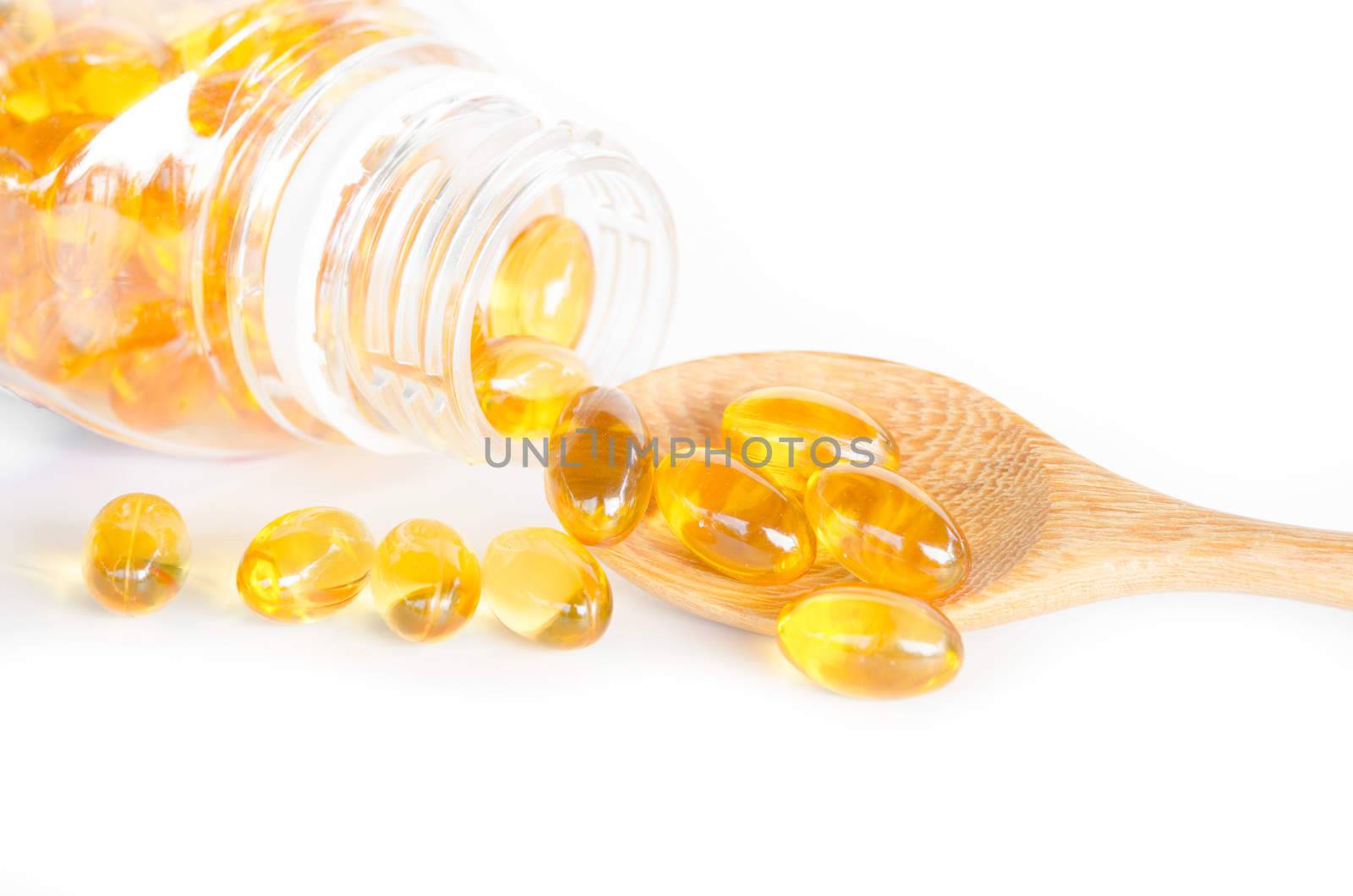 Fish oil capsules in a spoon on wooden background.
