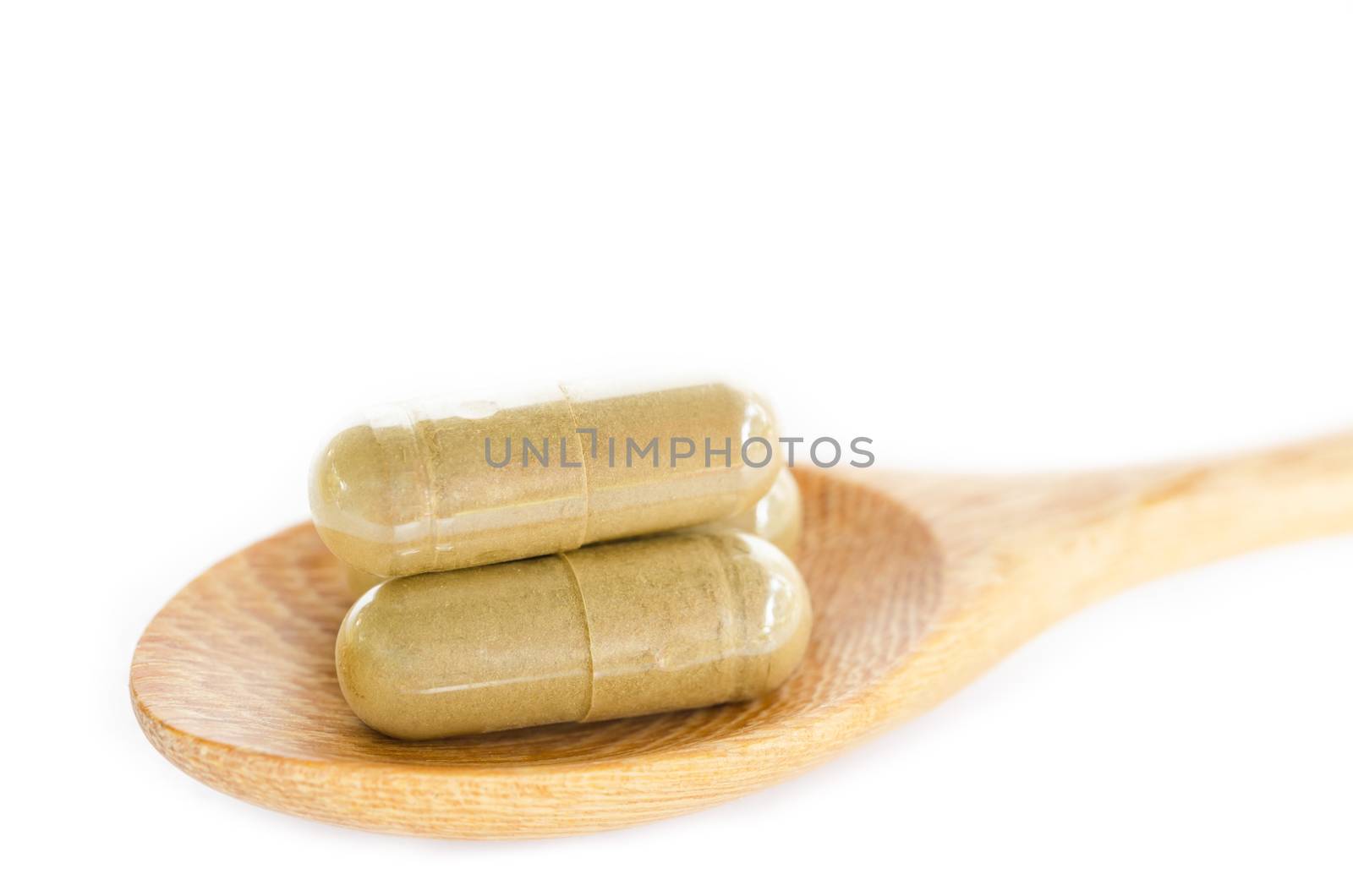 Organic capsule. Herb medical in wooden spoon on white background.