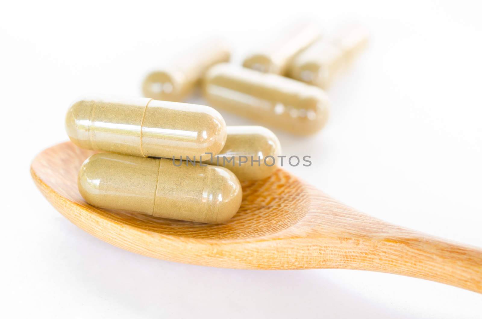 Close up image of herbal medicine in wooden spoon on white background.