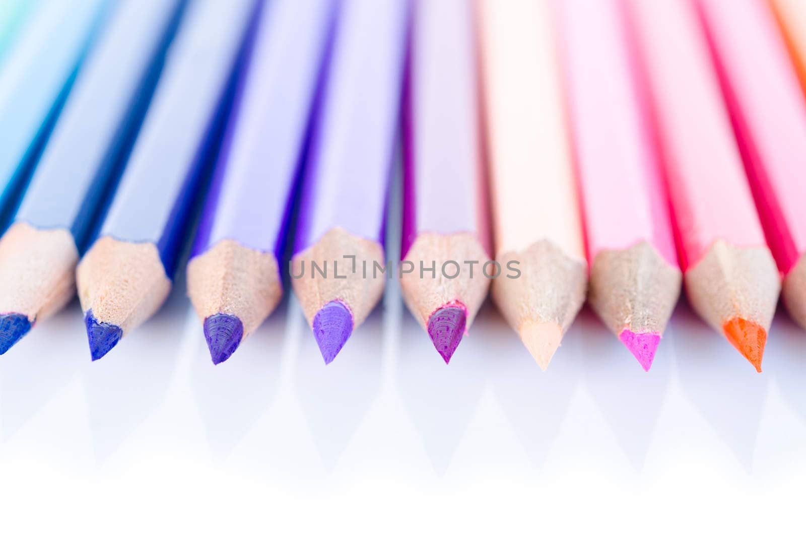 line of colored pencils with shadow on white background