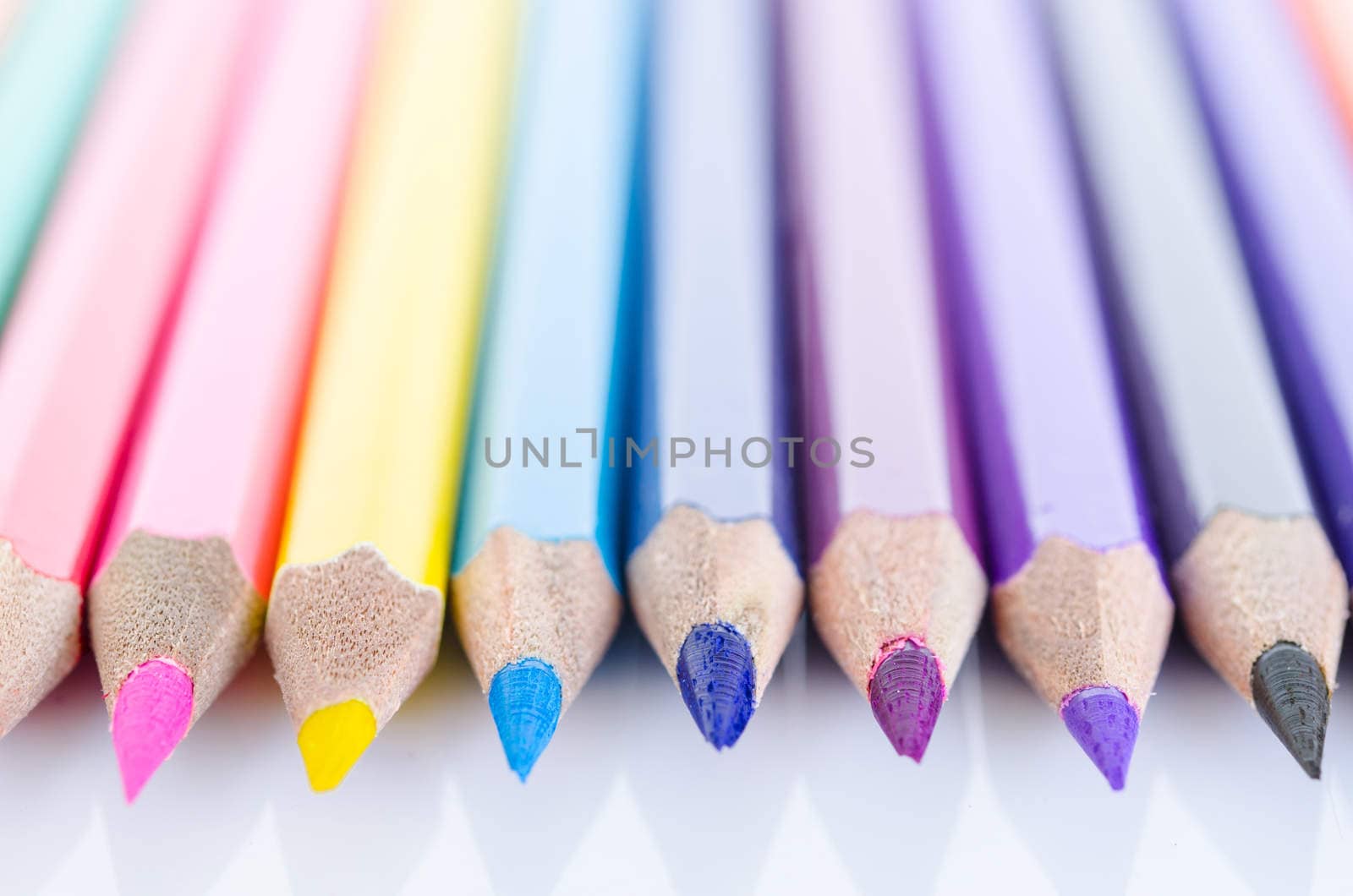 line of colored pencils with shadow on white background