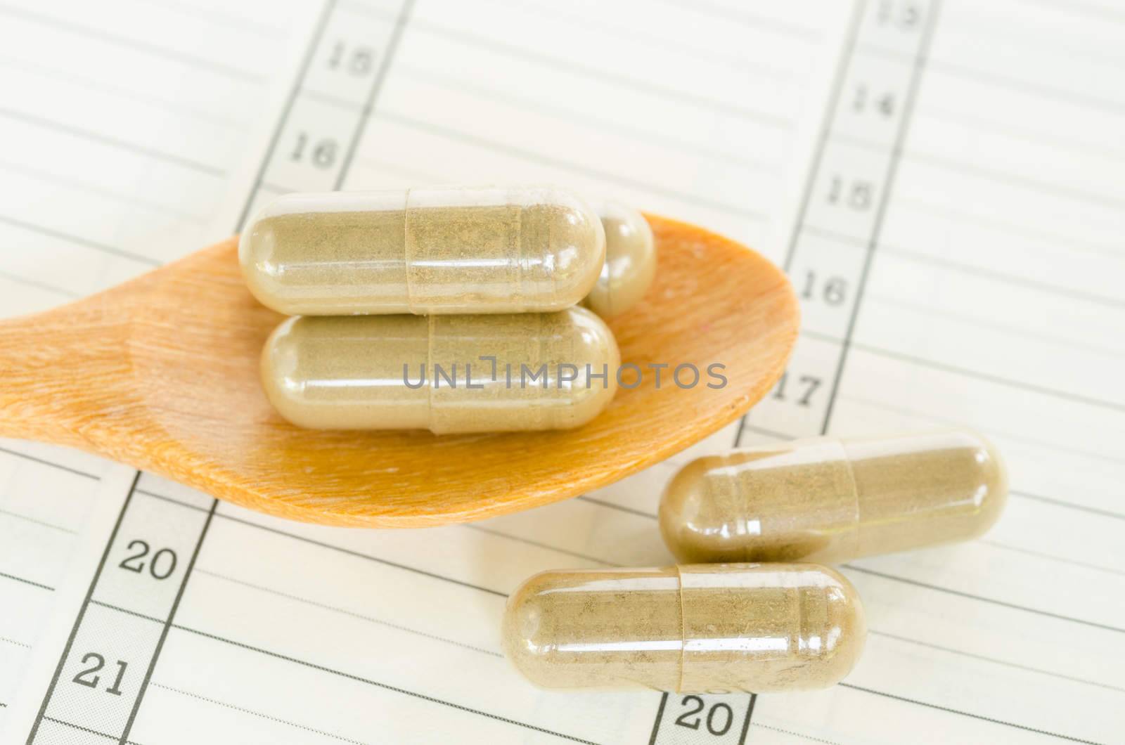 Yellow herb capsule medicine with on diary background.