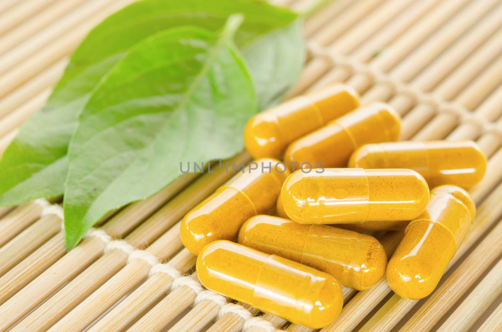 Yellow herbal medicine on wooden mat with leaf.