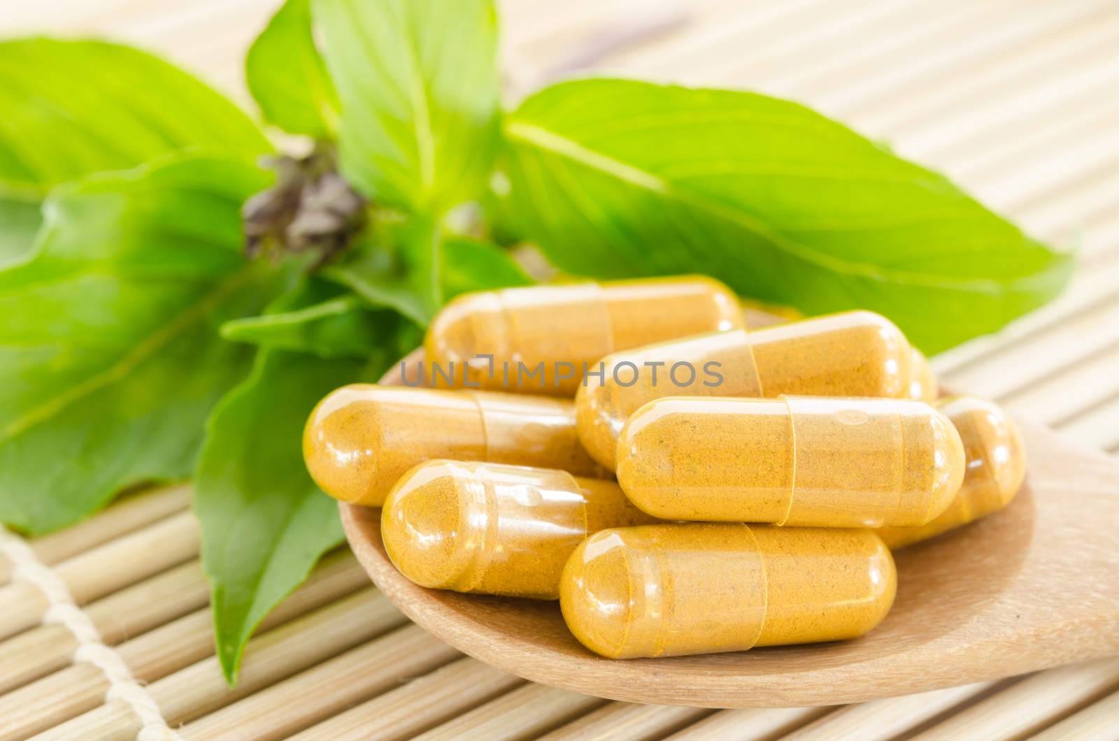 Alternative medicine tablets on a wooden mat, green leaf.