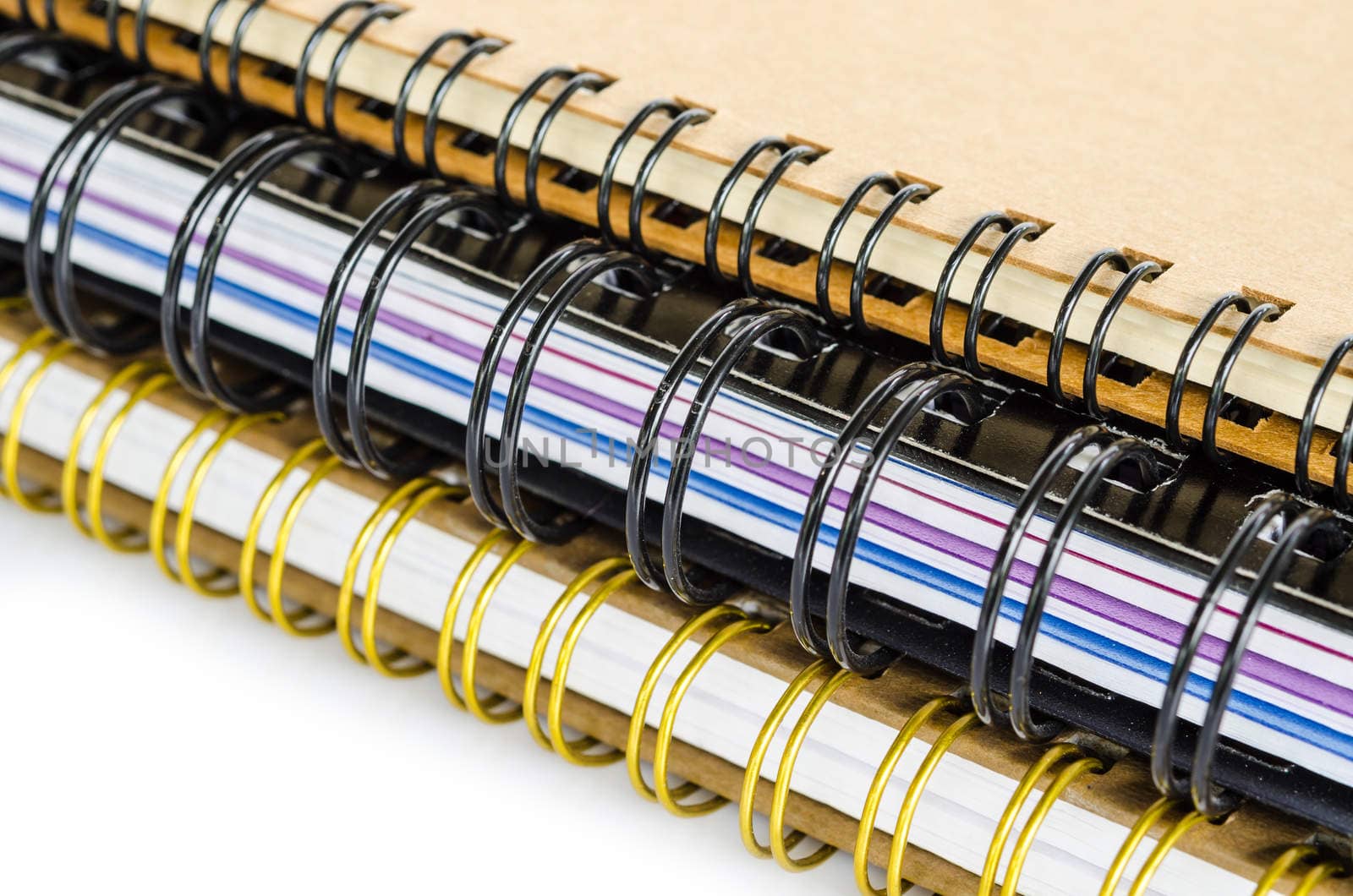 Three closed spiral notebooks in a pile on white background.