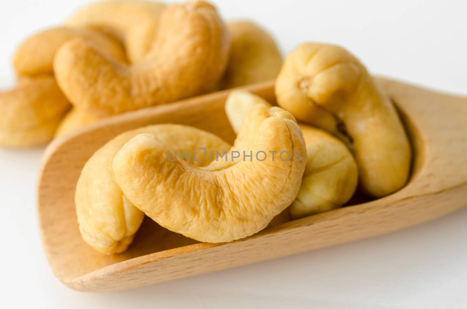 cashew nuts in wooden spoon on white background.